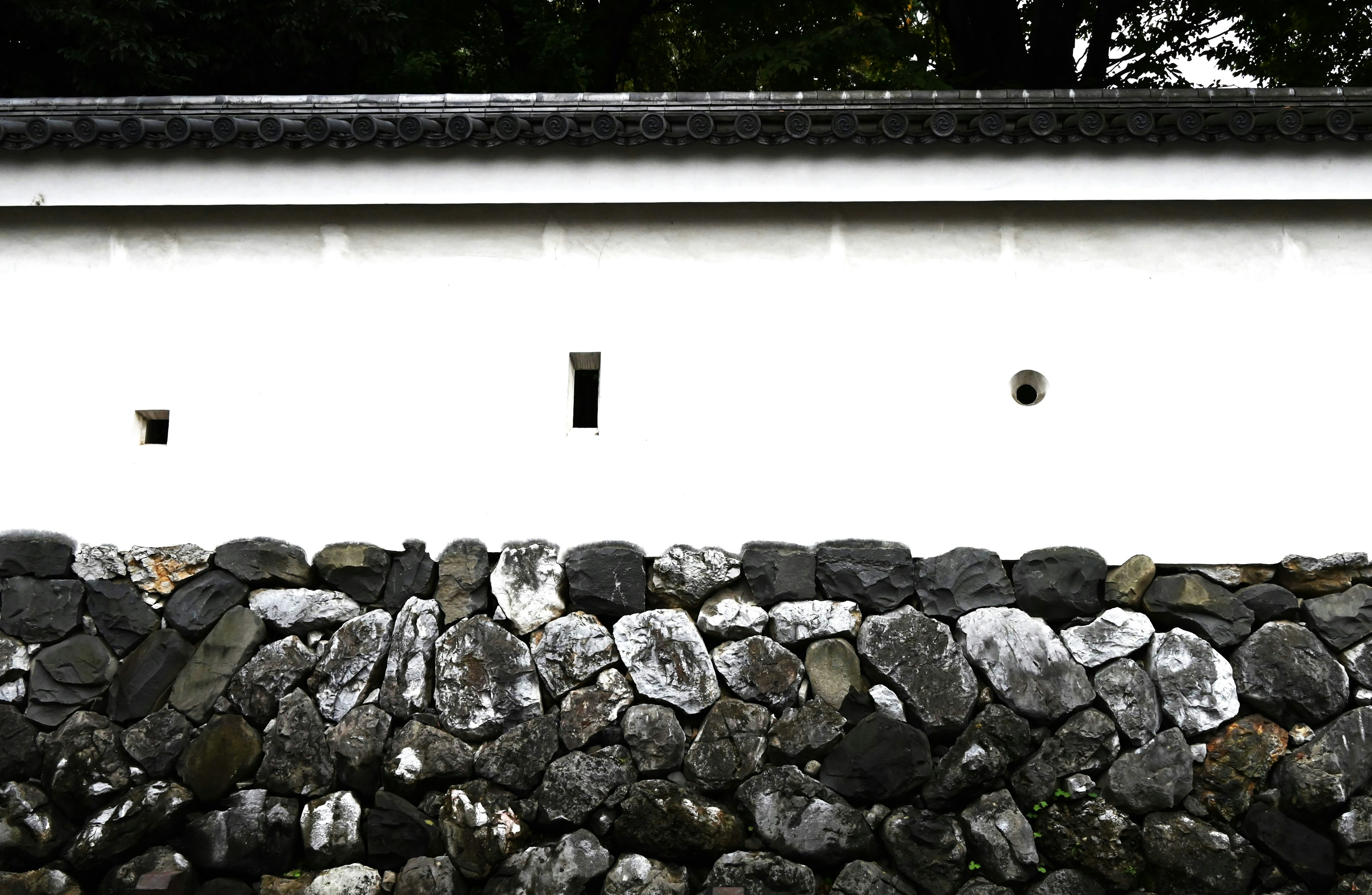 Architecture japonaise traditionnelle avec un mur blanc et une fondation en pierre