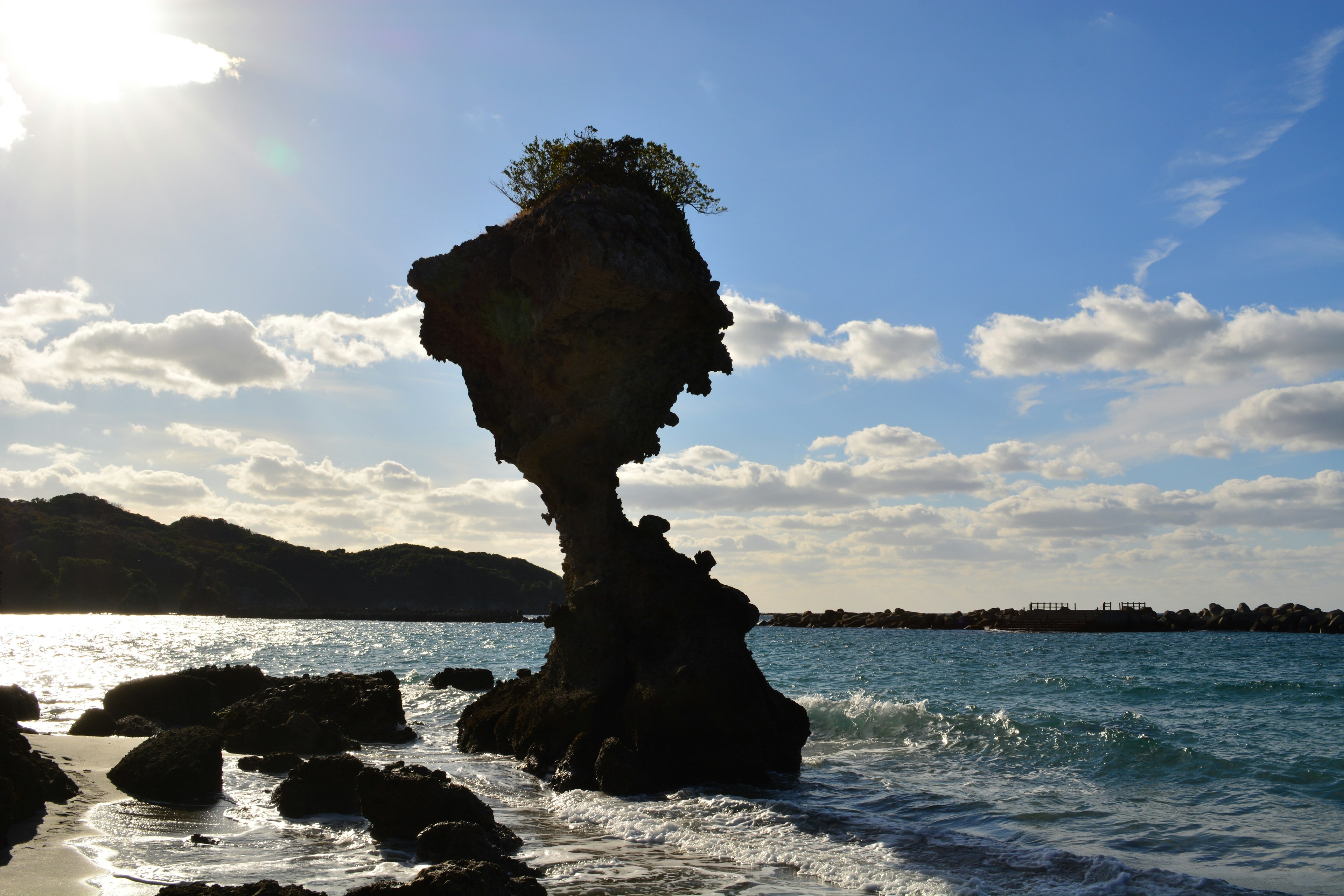 Einzigartige Felsformation, die einem Gesicht ähnelt, am Meer mit blauem Himmel