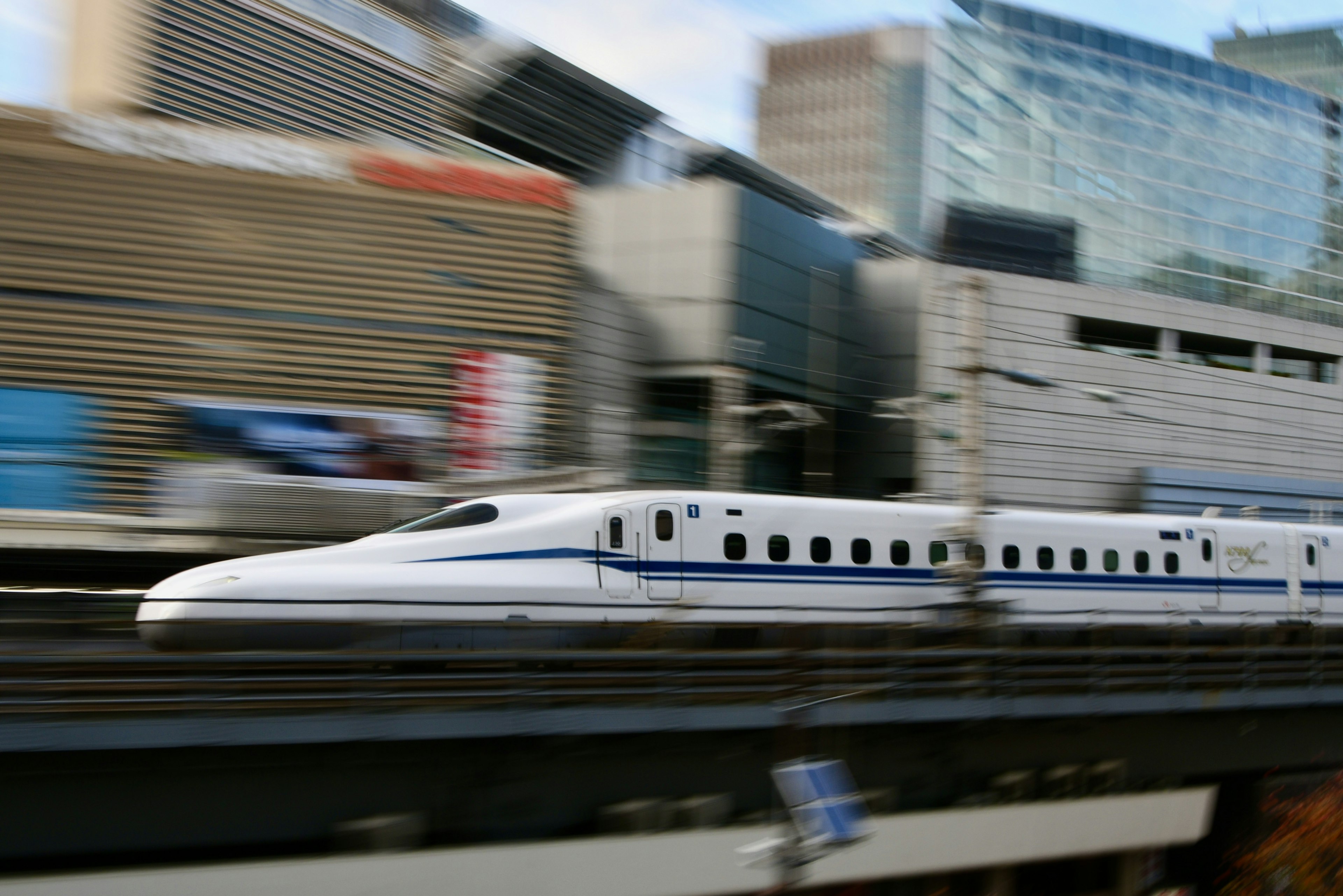 Shinkansen che sfreccia davanti a un'architettura urbana