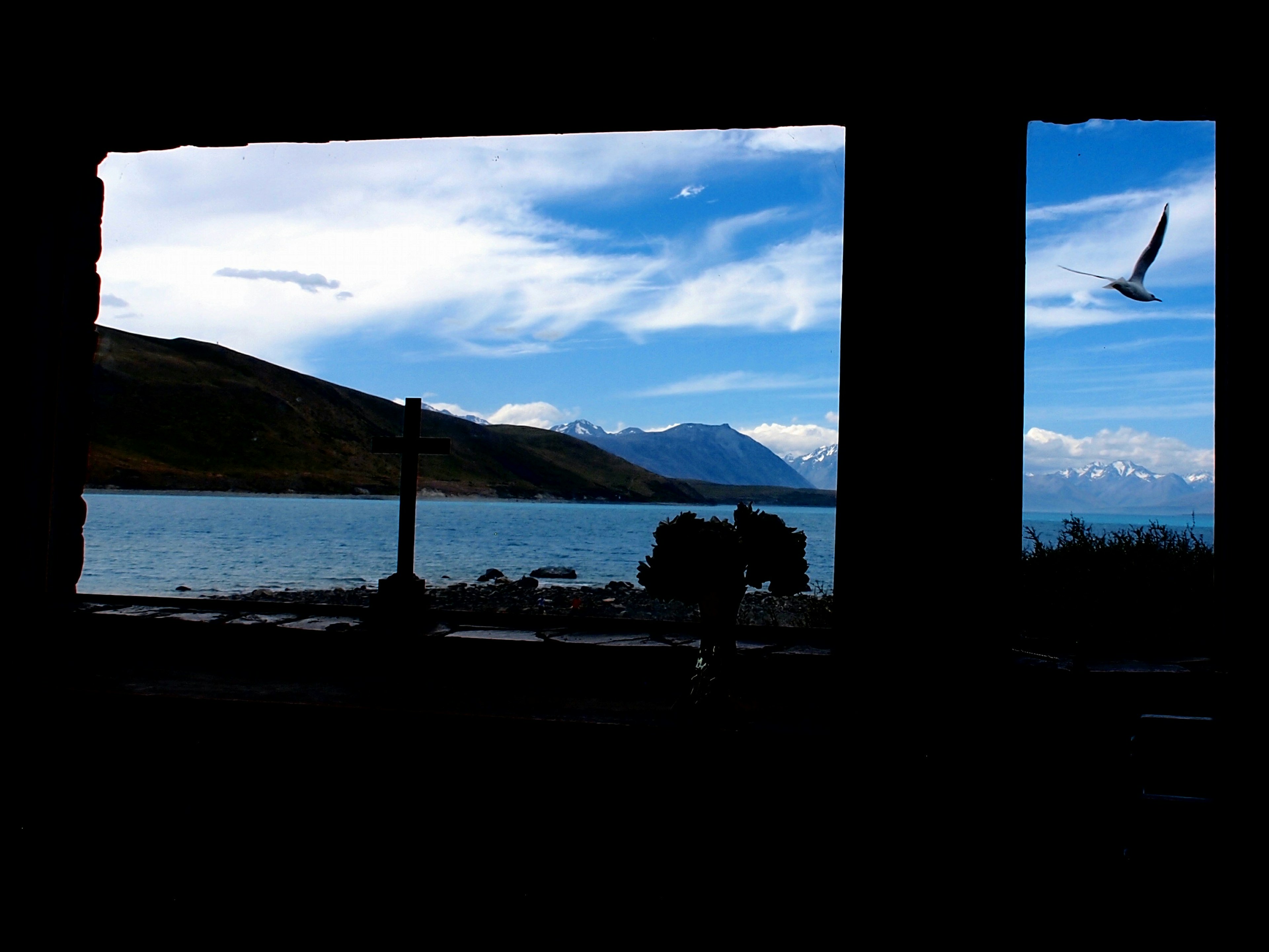 Vue panoramique d'un lac bleu et de montagnes enneigées à travers une fenêtre