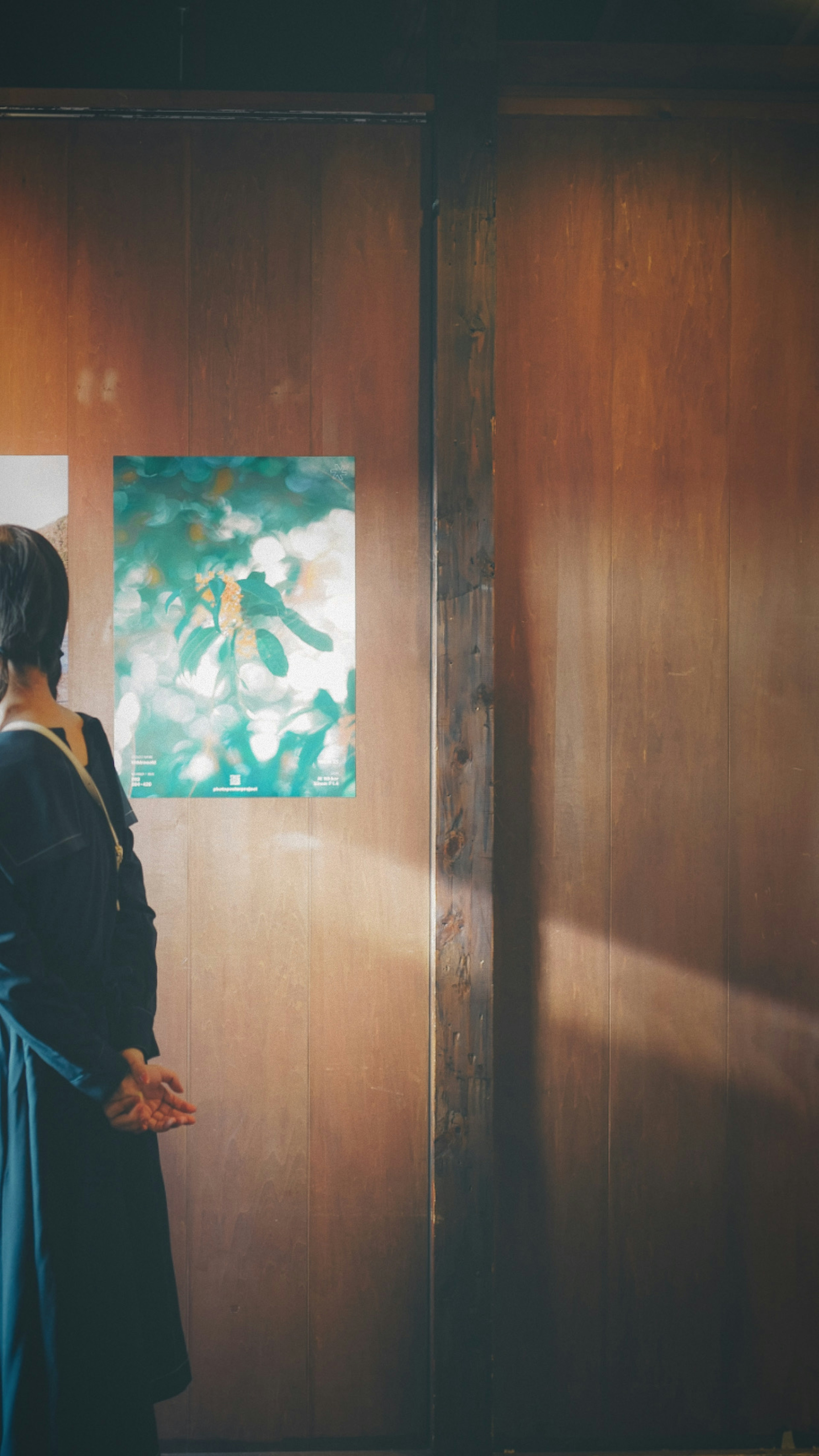 Woman standing in a room with wooden walls and a painting