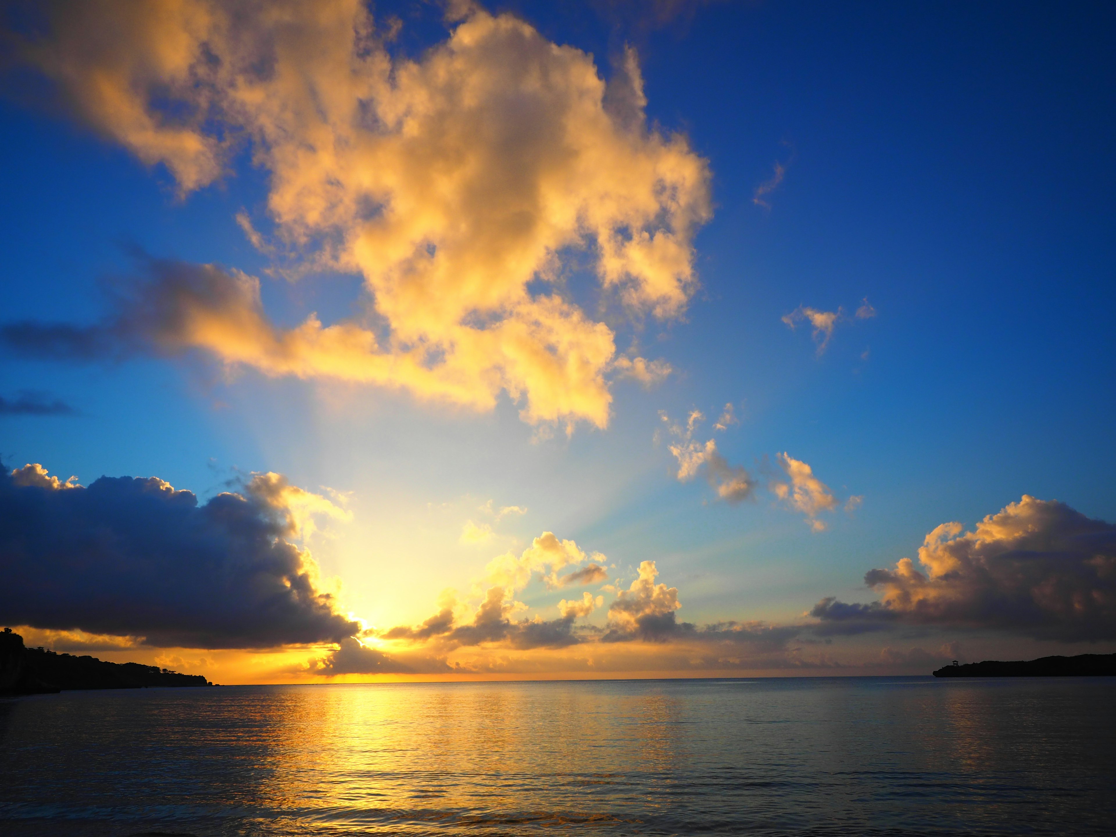 Wunderschöner Sonnenuntergang über dem Ozean mit Wolken im blauen Himmel