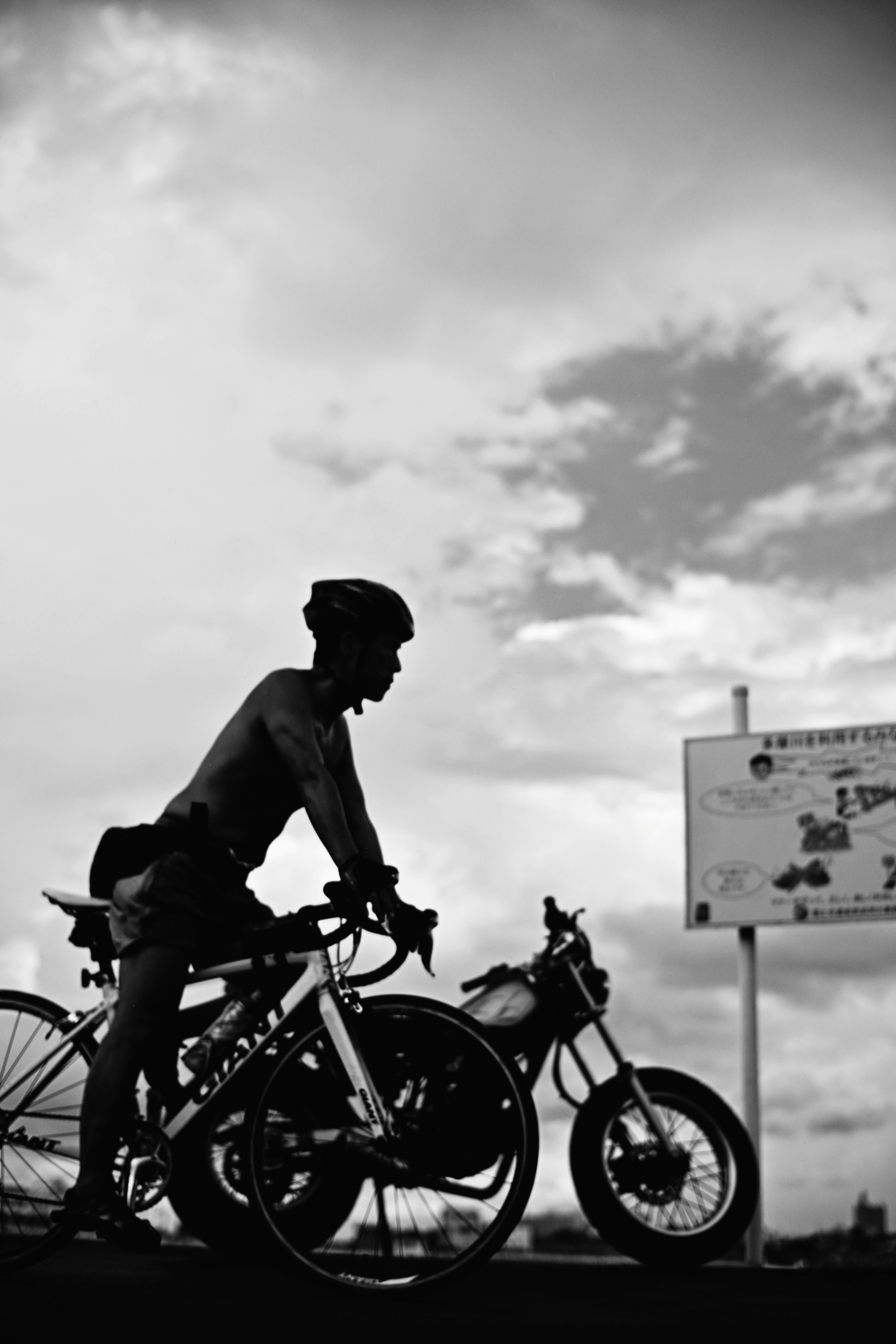 Silhouette di un uomo in piedi accanto a una bicicletta e a una moto