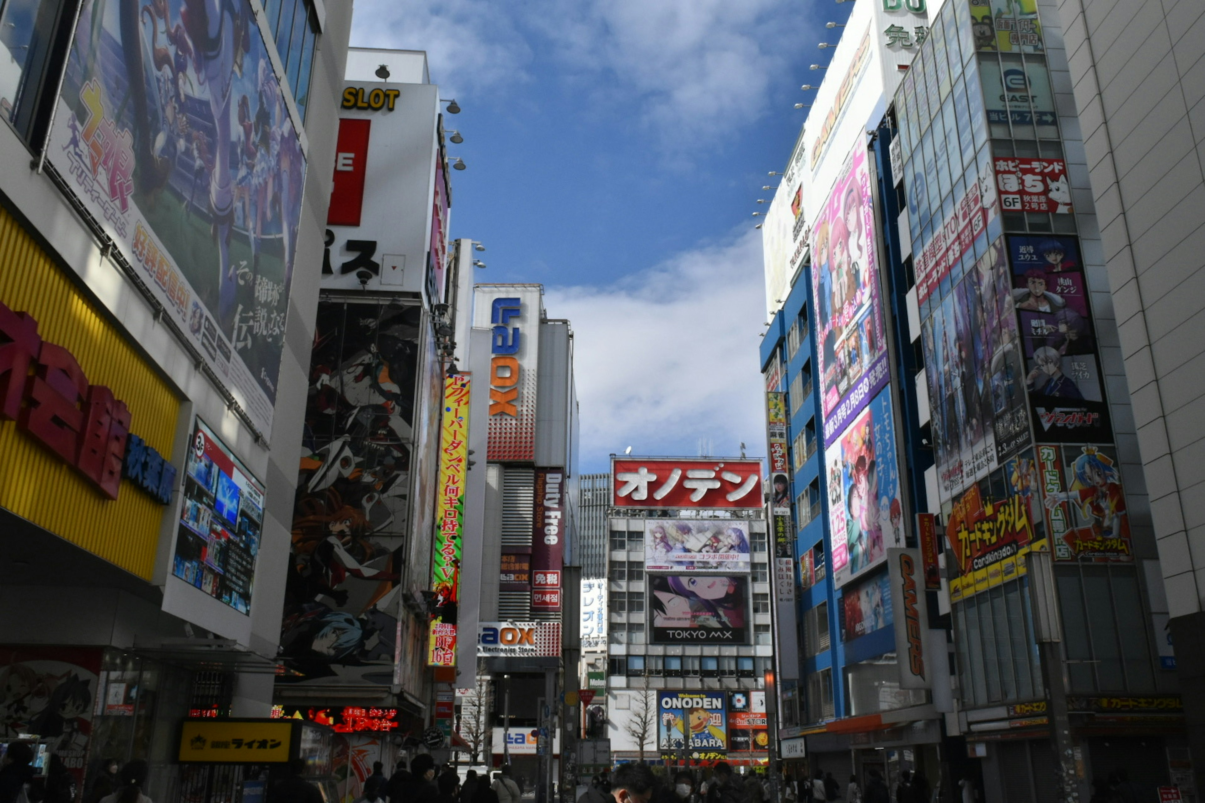 Belebte Straße in Akihabara mit hohen Gebäuden und bunten Werbetafeln