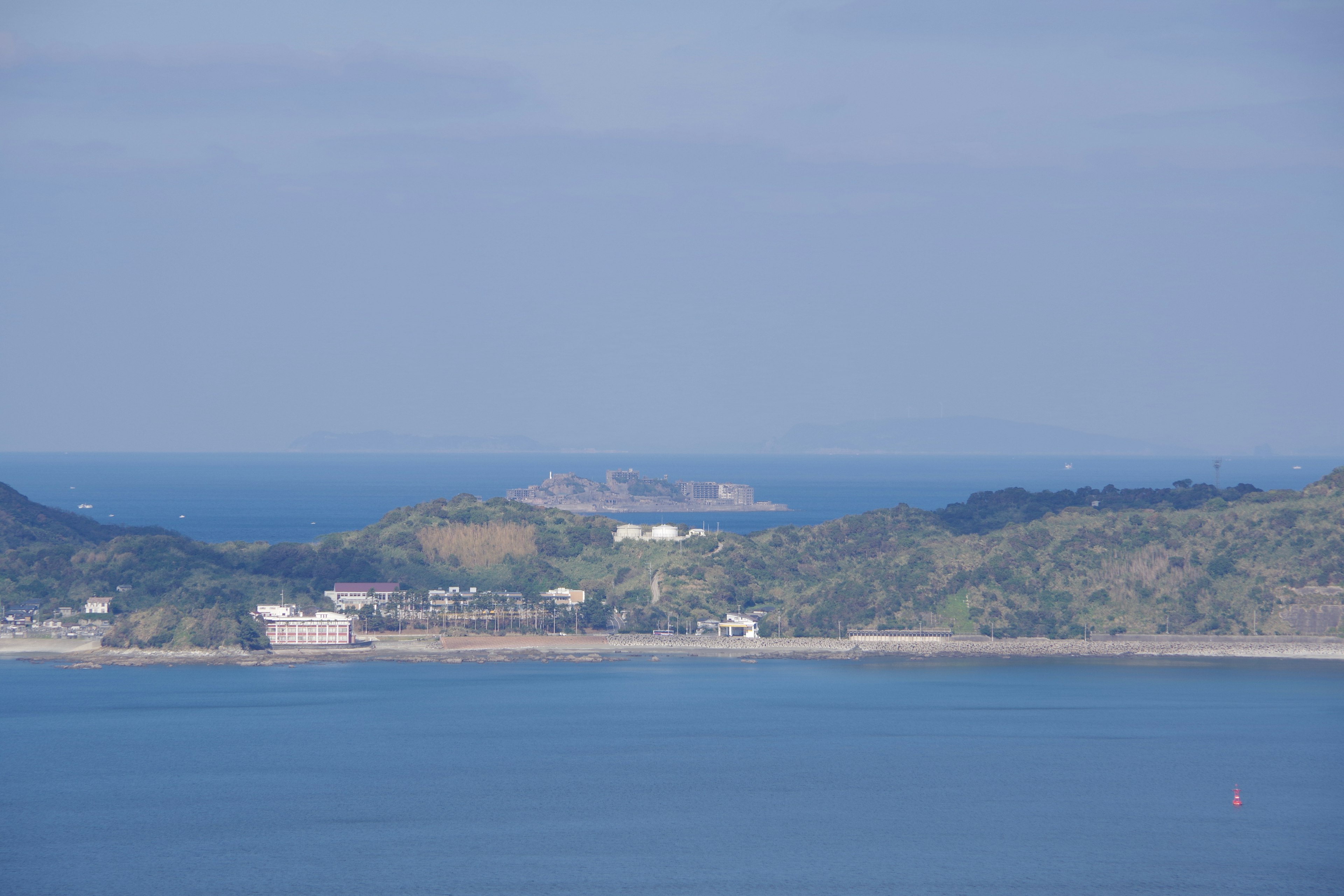 Pemandangan laut biru dengan bukit hijau dan pulau jauh