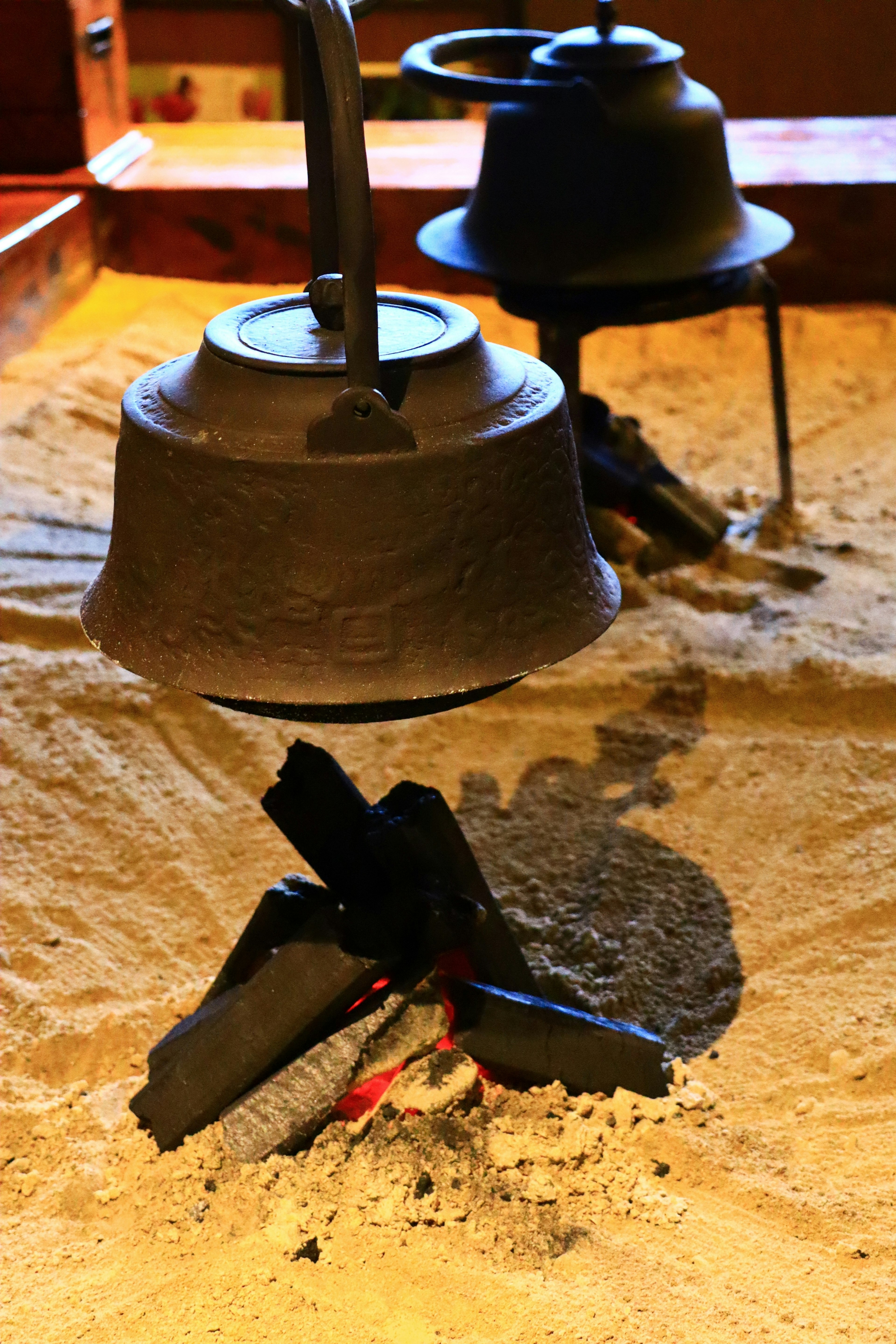 Zwei Töpfe über einem kleinen Feuer auf Sand aufgehängt