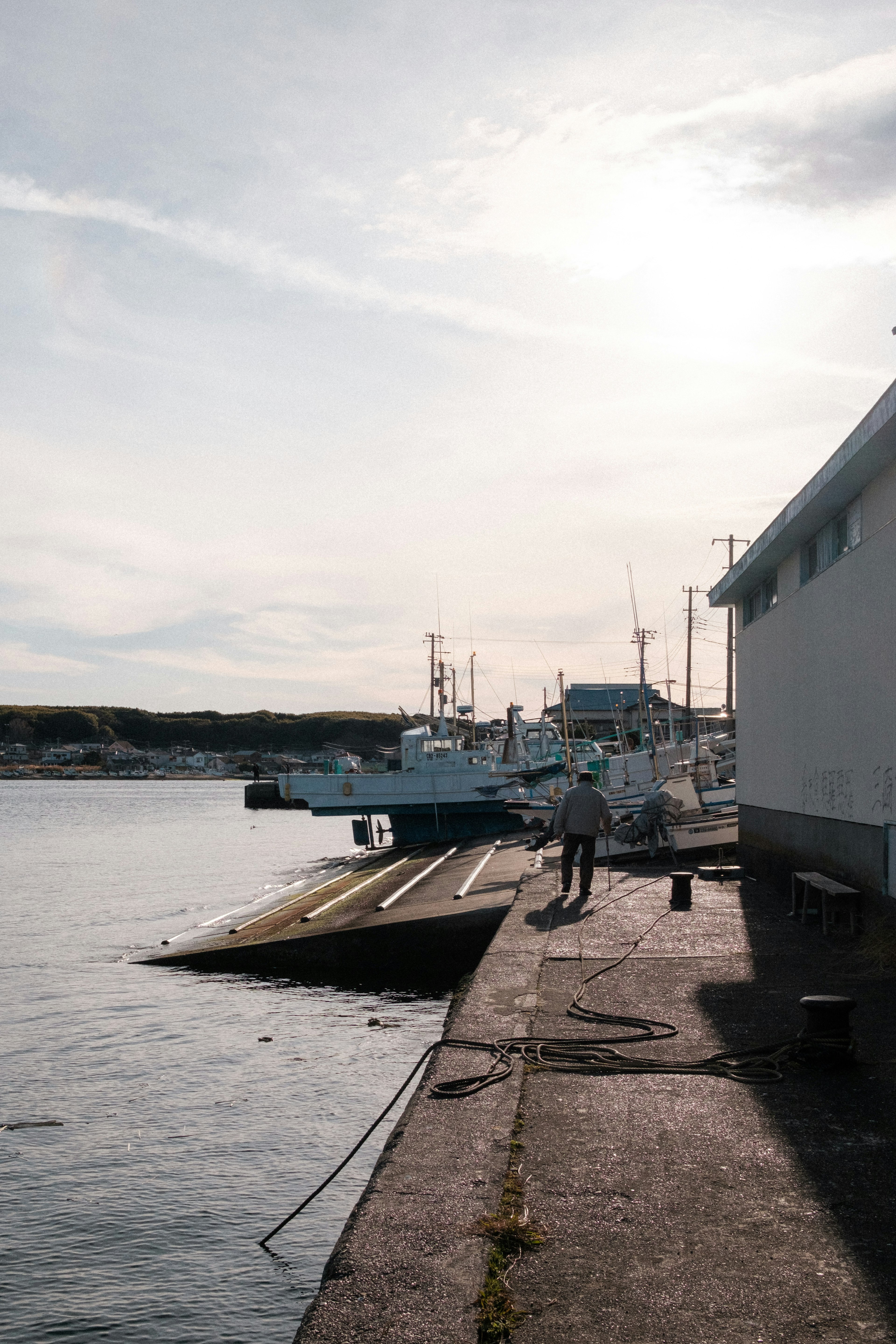 Silhouette d'une personne travaillant sur le rivage avec des bateaux amarrés dans le port