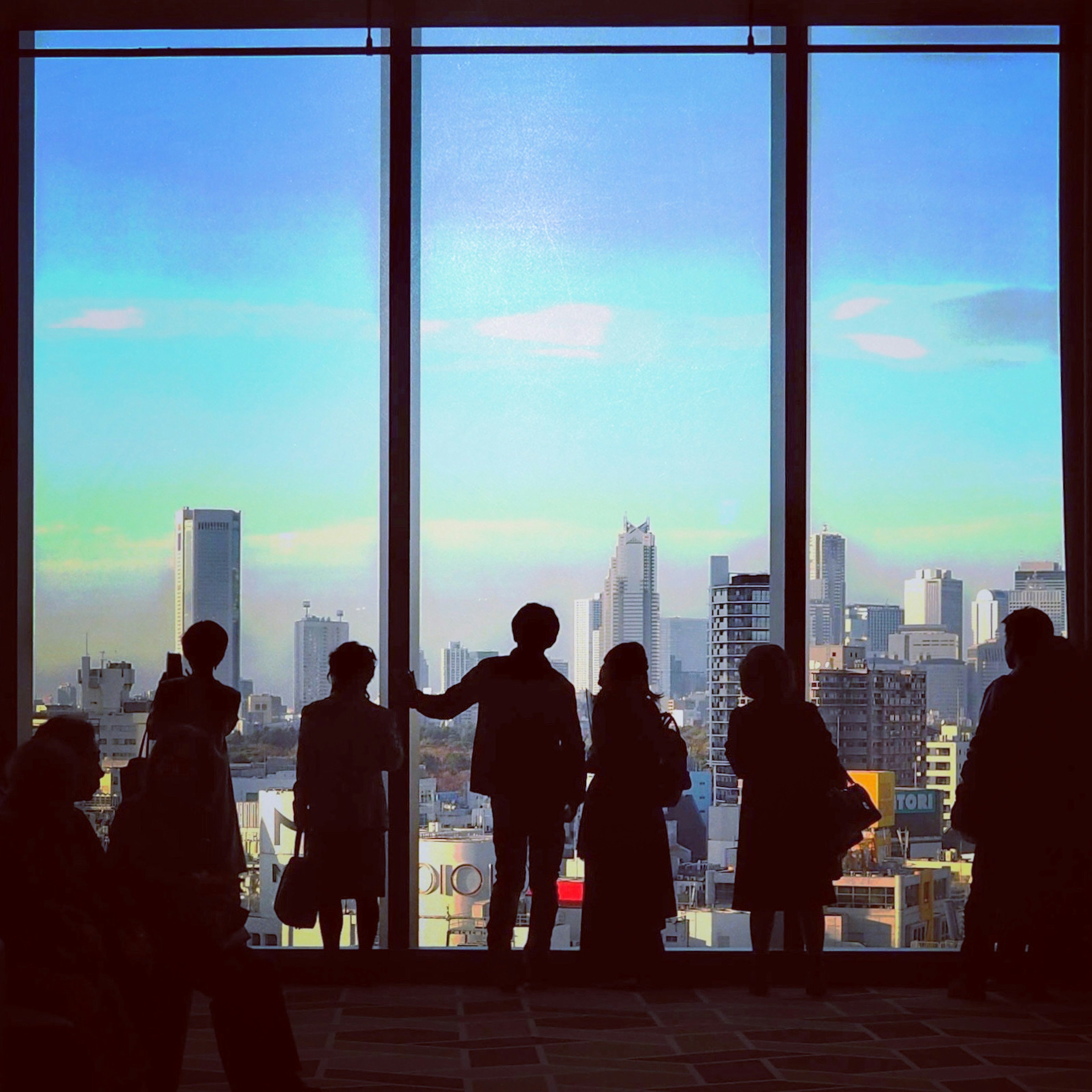 Silhouette di persone davanti a una finestra con skyline cittadino