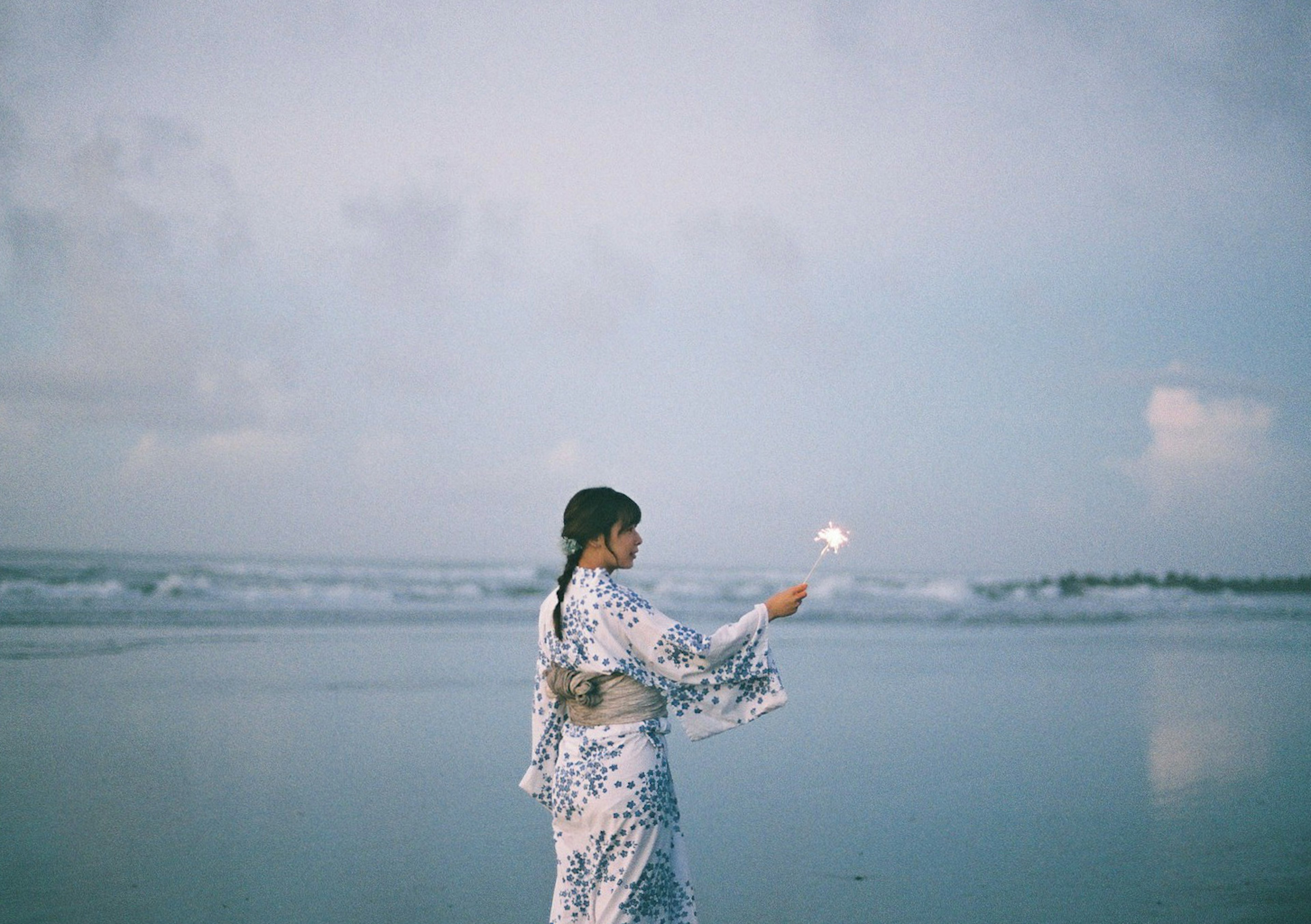 海辺で光る花火を持つ着物姿の女性