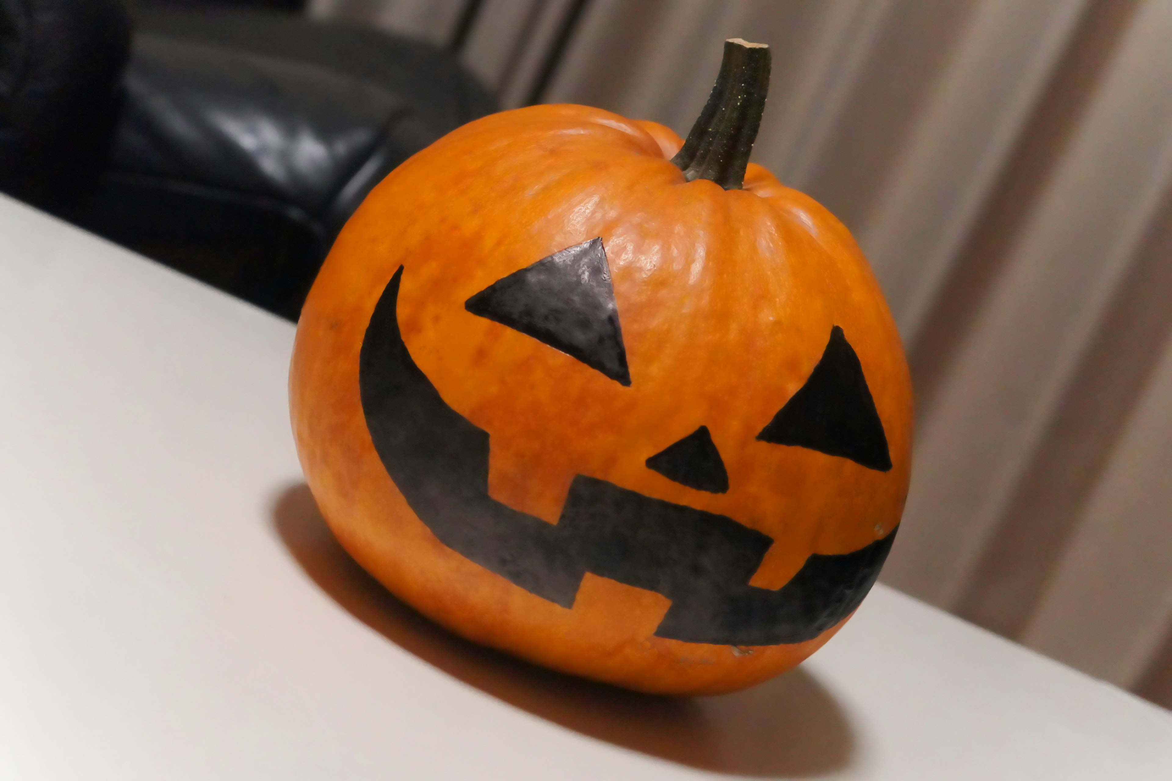 An orange jack-o'-lantern pumpkin featuring a black face design