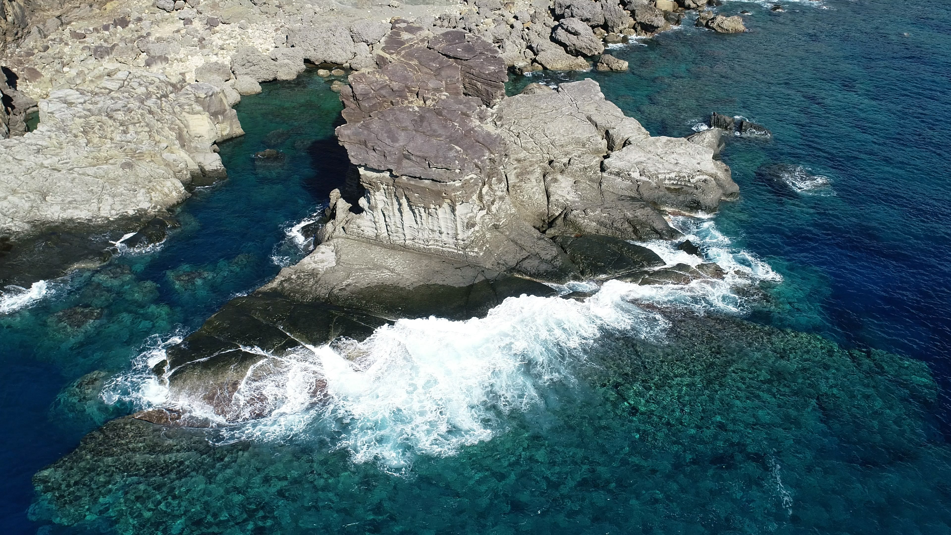 Pemandangan udara dari pantai berbatu dengan ombak yang menghantam