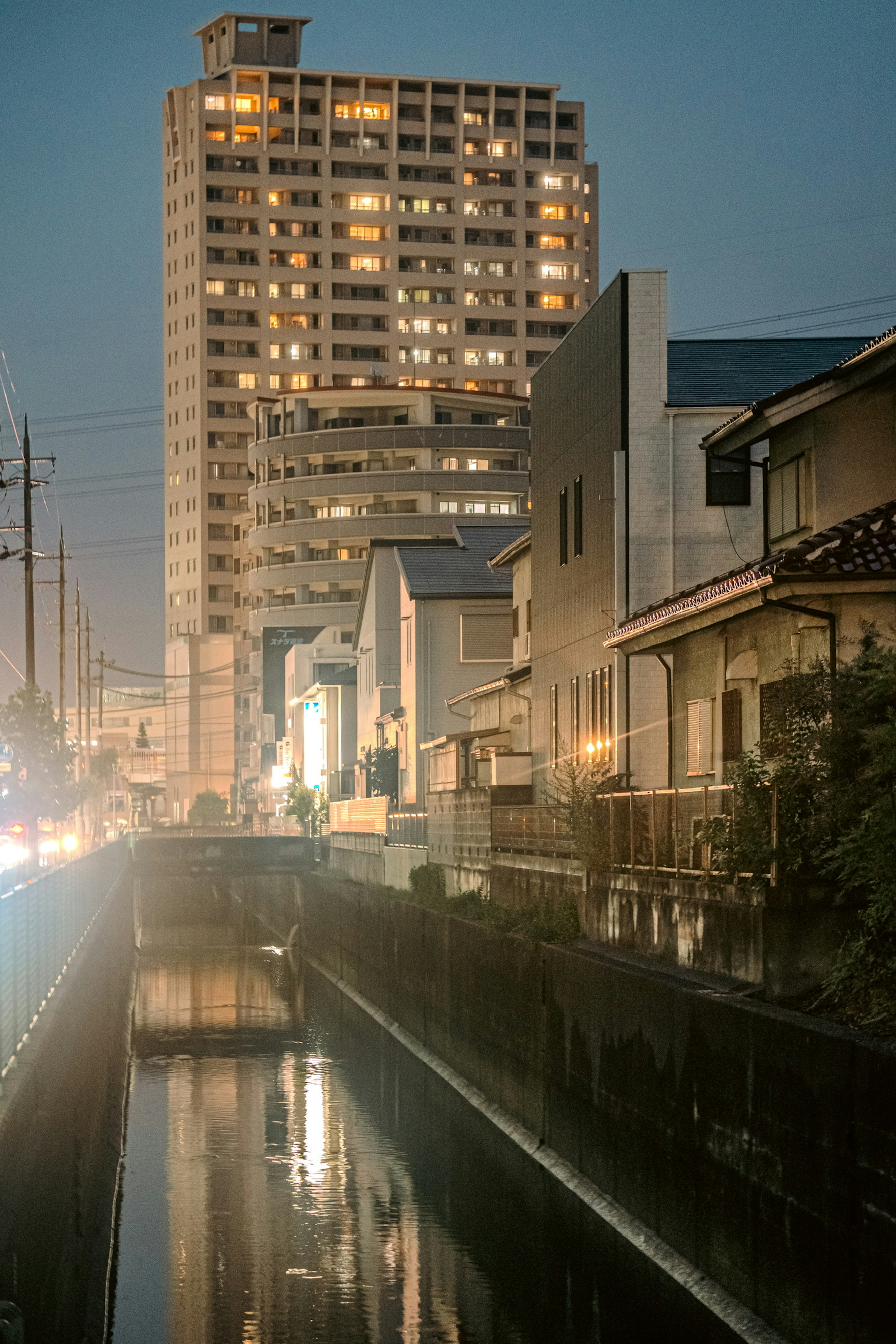 Pemandangan kota malam dengan pantulan di air yang menunjukkan arsitektur Jepang