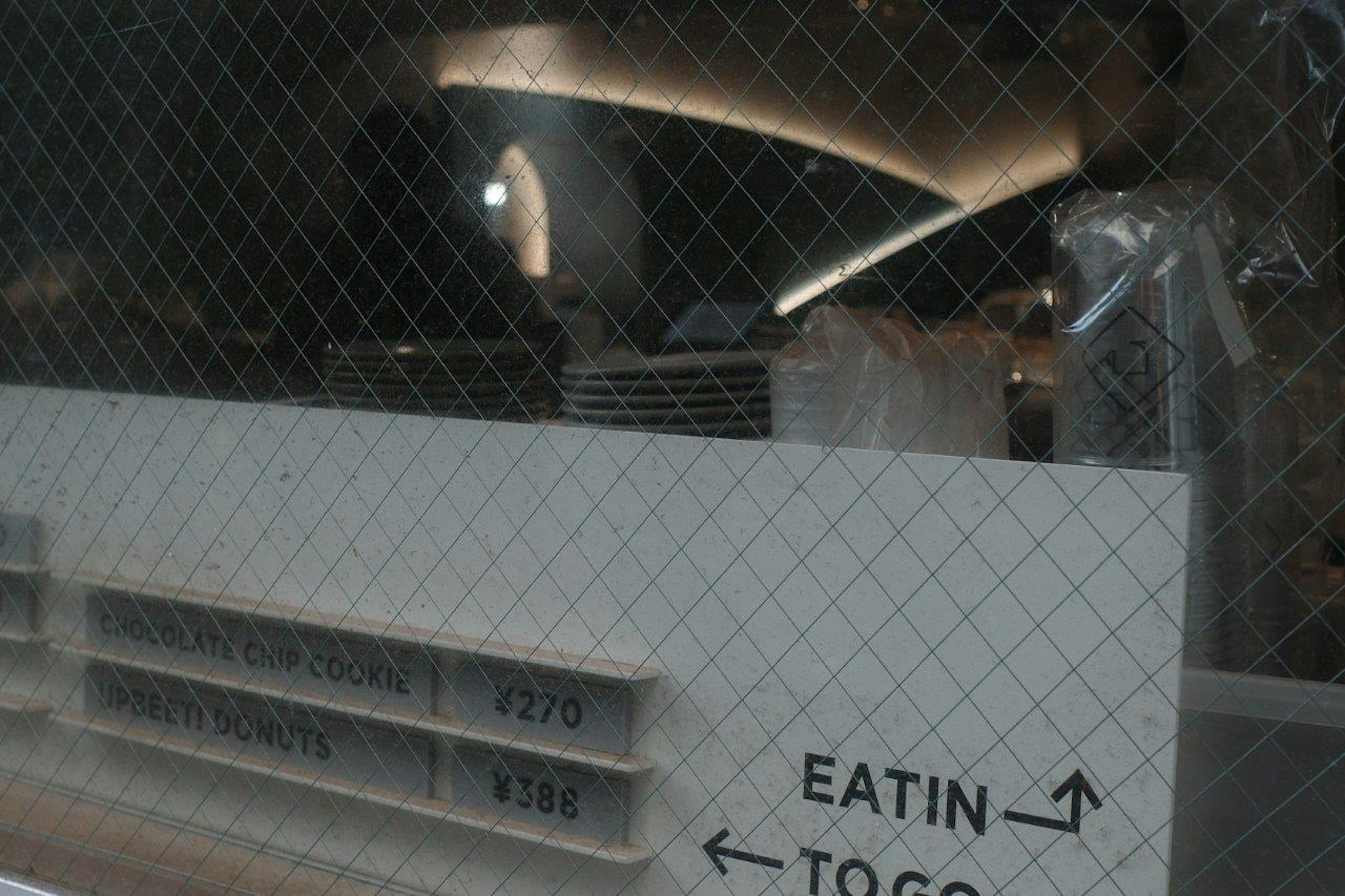 View of a restaurant sign indicating EATIN and TO GO through a glass window