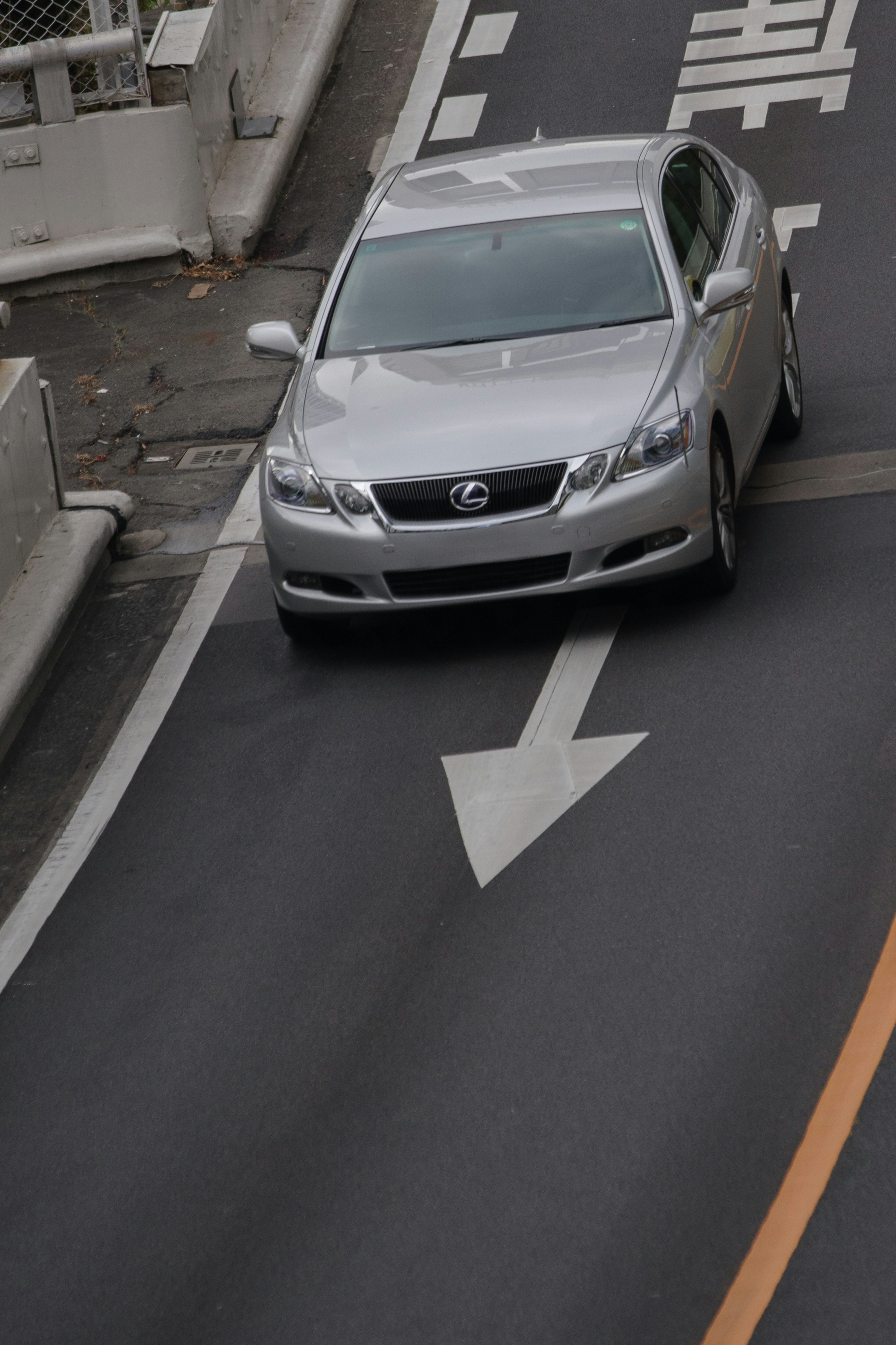 银色汽车在弯曲的道路上行驶，带有方向标志