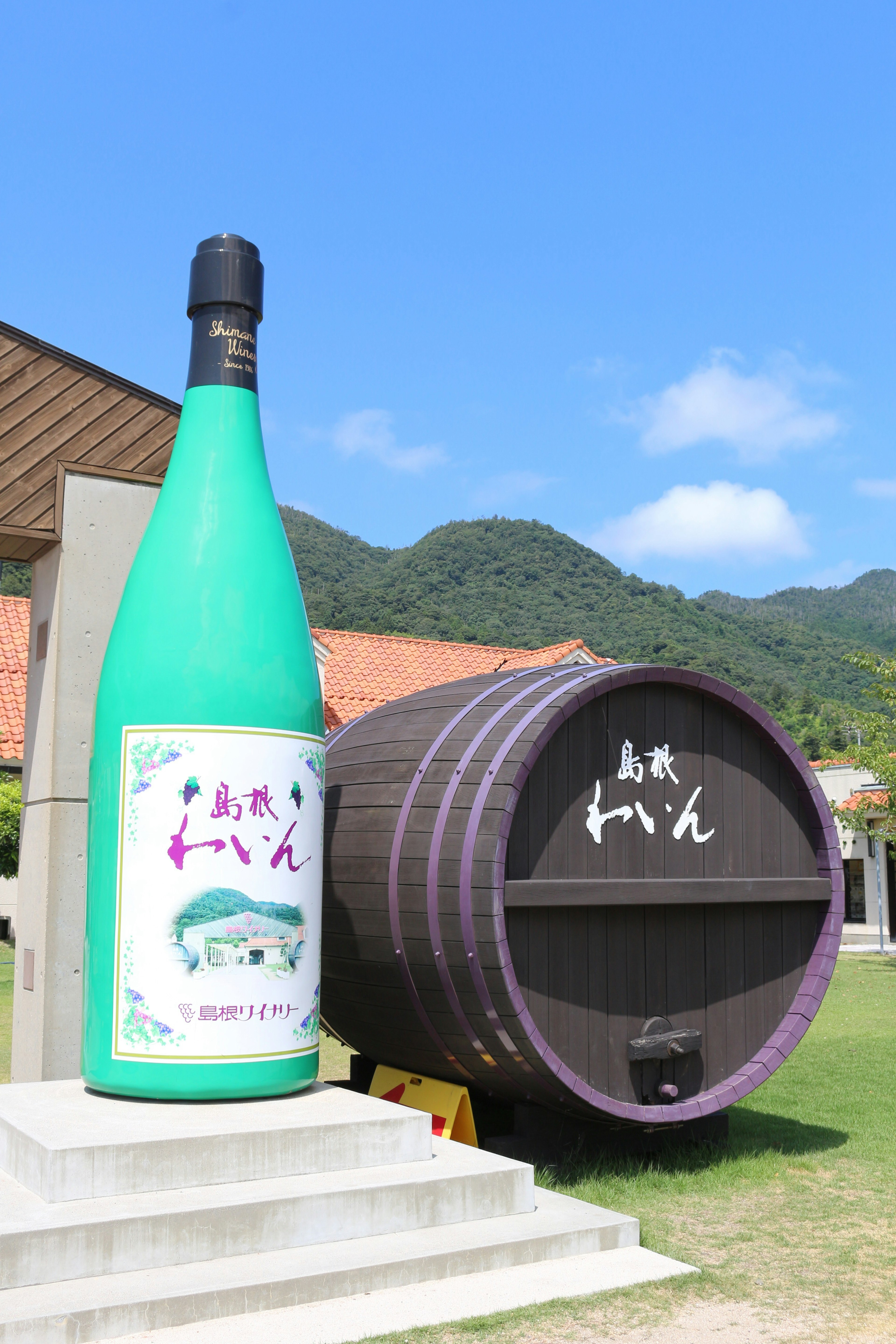 Gran exhibición de una botella de sake y un barril bajo un cielo azul