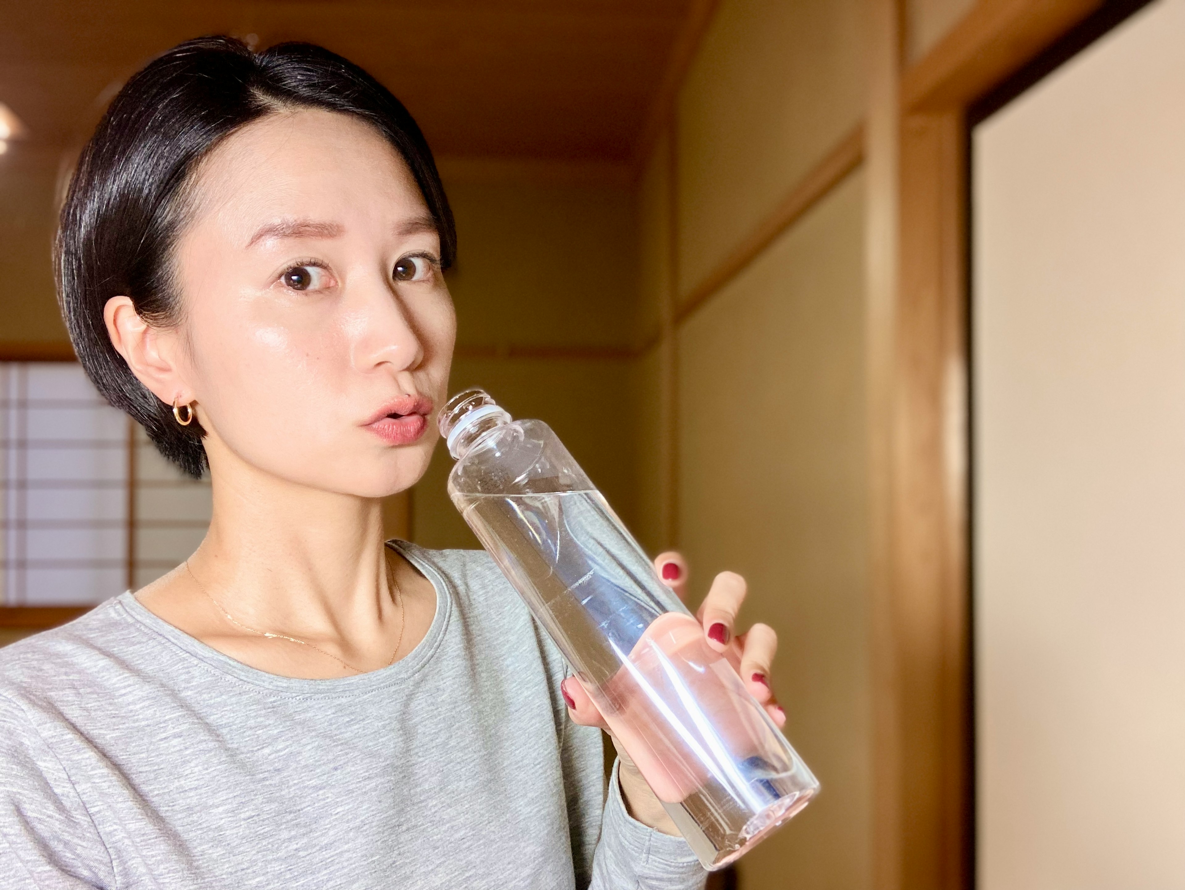 Woman holding a clear water bottle with a playful expression