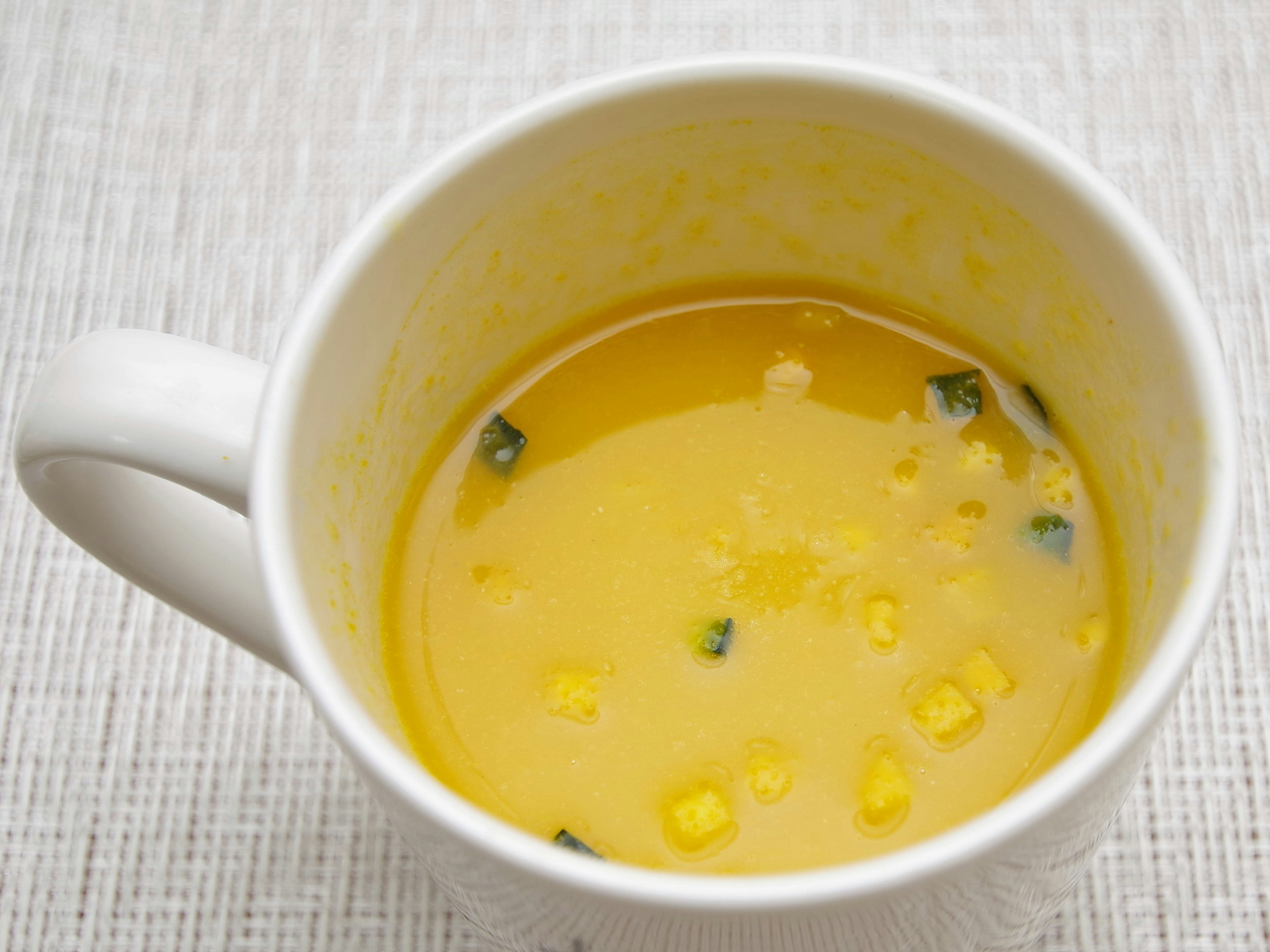 Gelbe Suppe in einer weißen Tasse