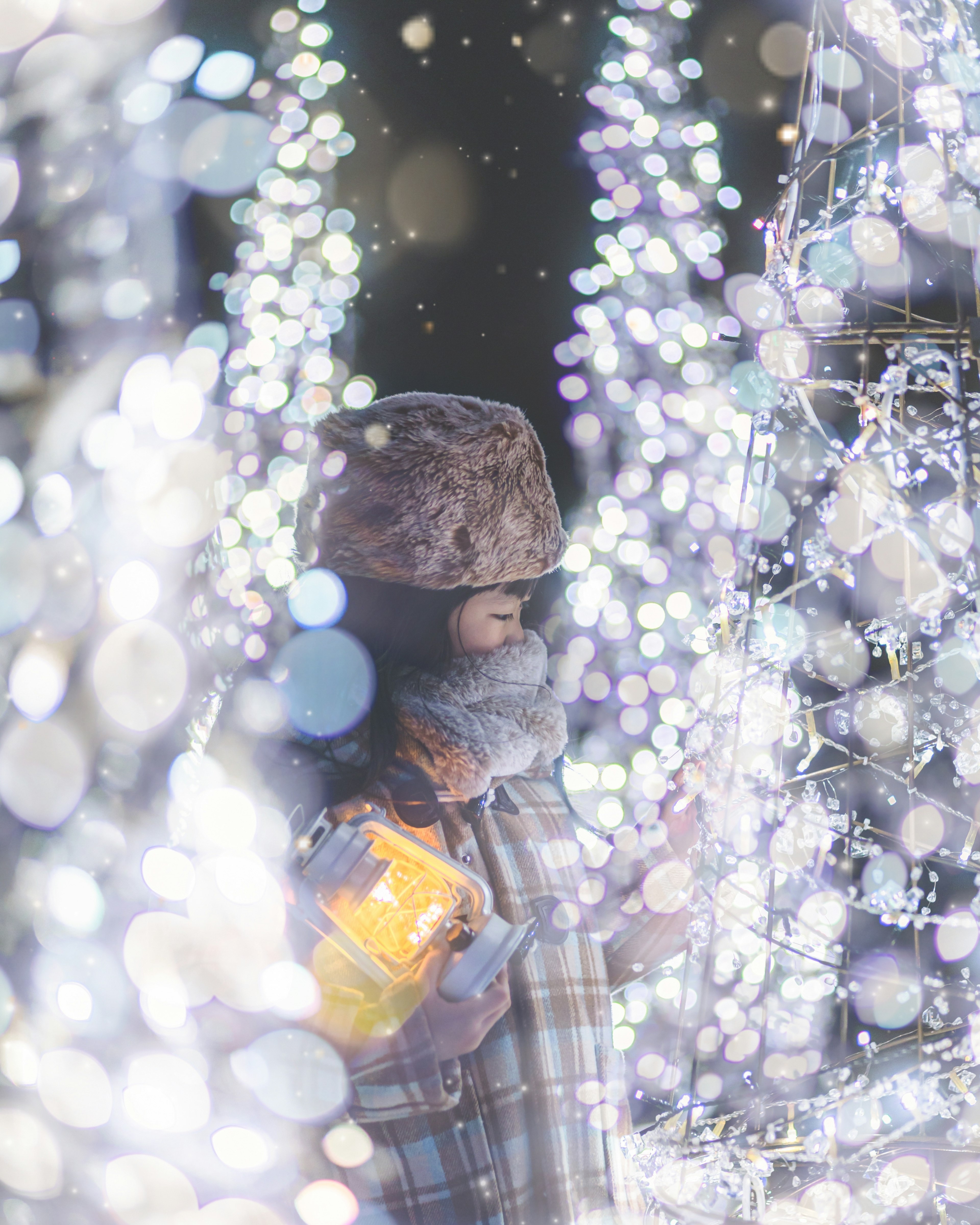 Bambino in abbigliamento invernale che guarda decorazioni luminose