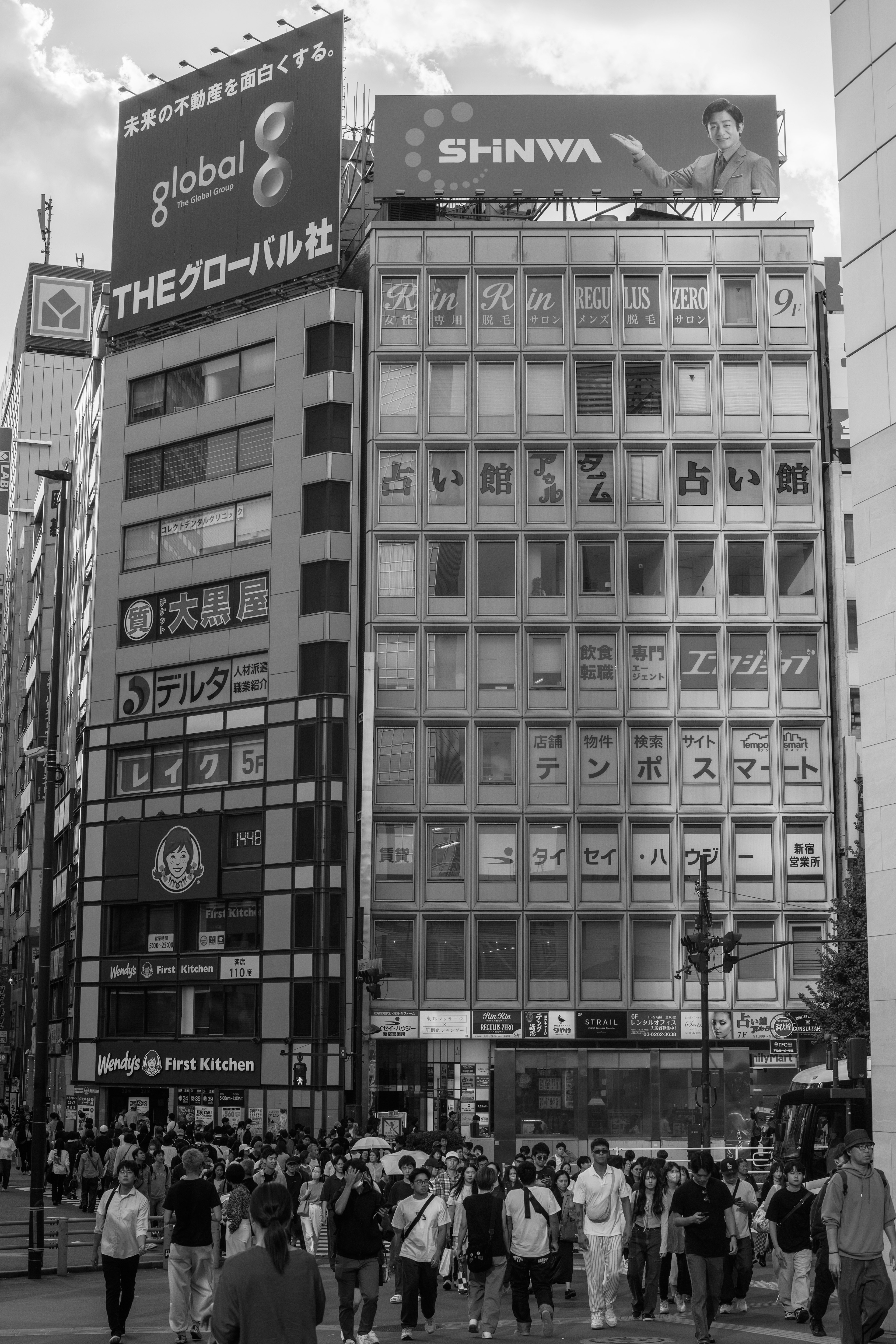 Escena urbana en blanco y negro con personas caminando y edificios comerciales