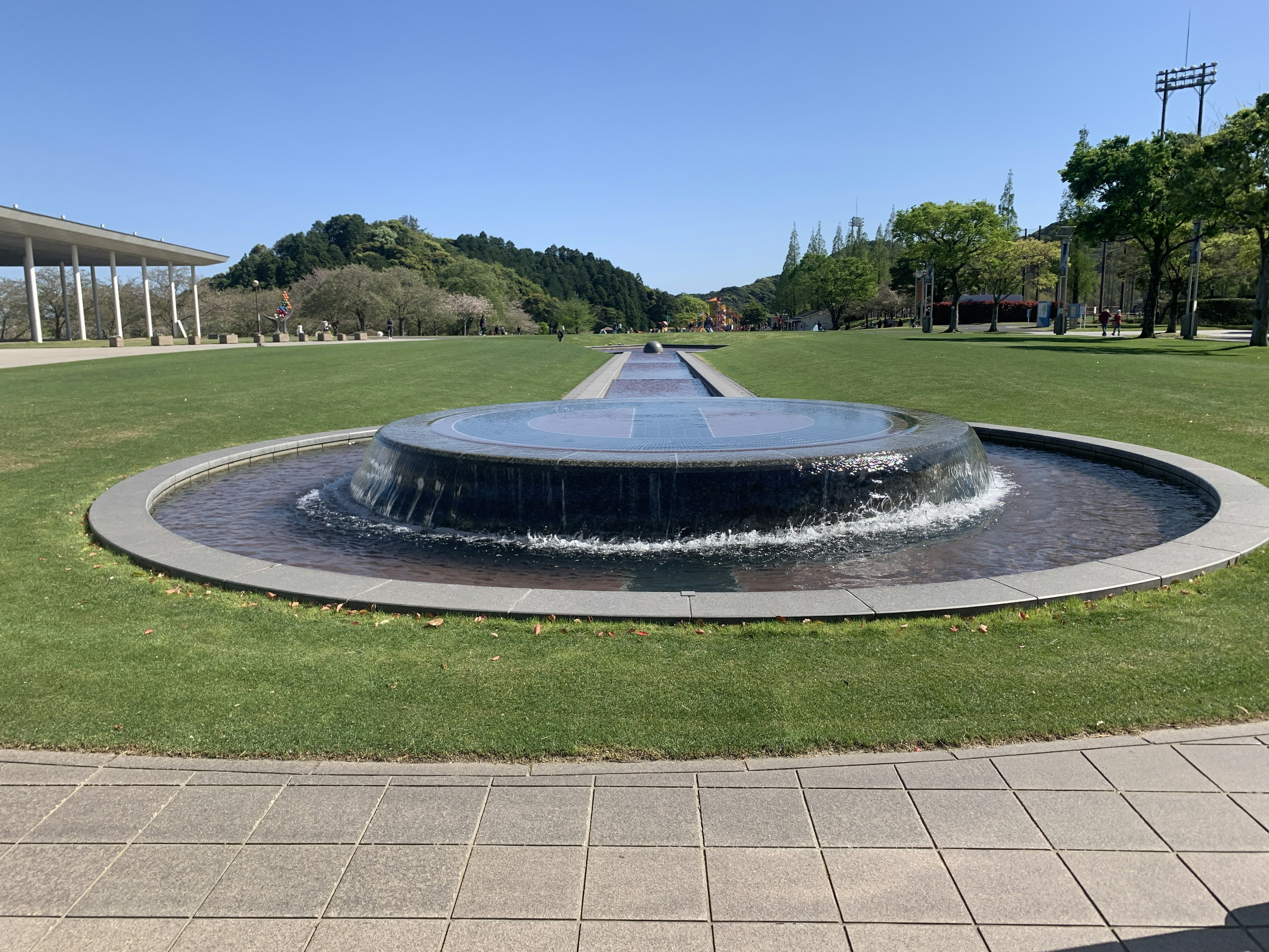 Circular fountain in a park surrounded by green grass