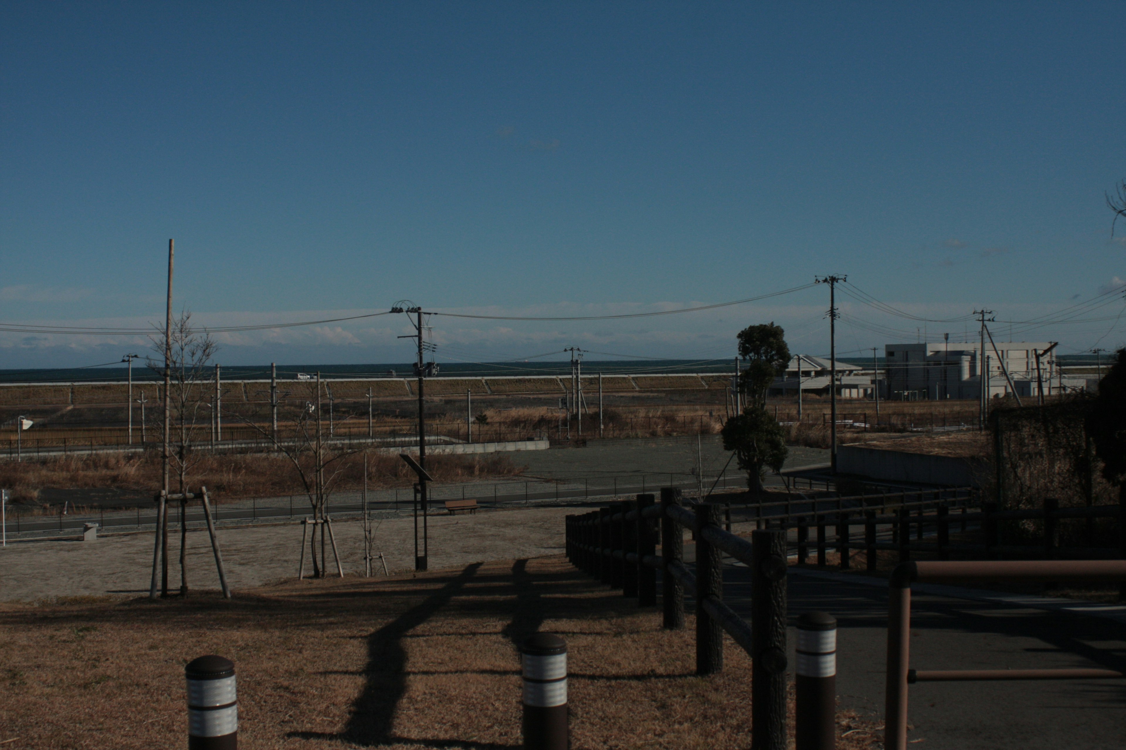 Landscape with ocean and sky visible distant buildings and power poles