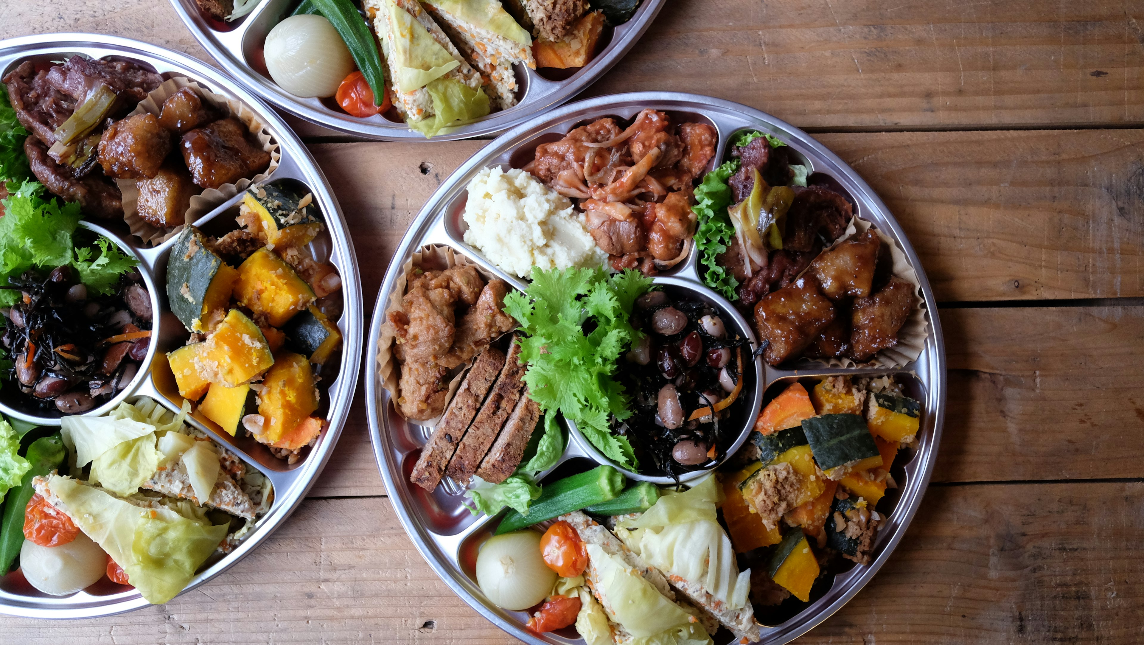 Three plates of colorful dishes arranged on a wooden table