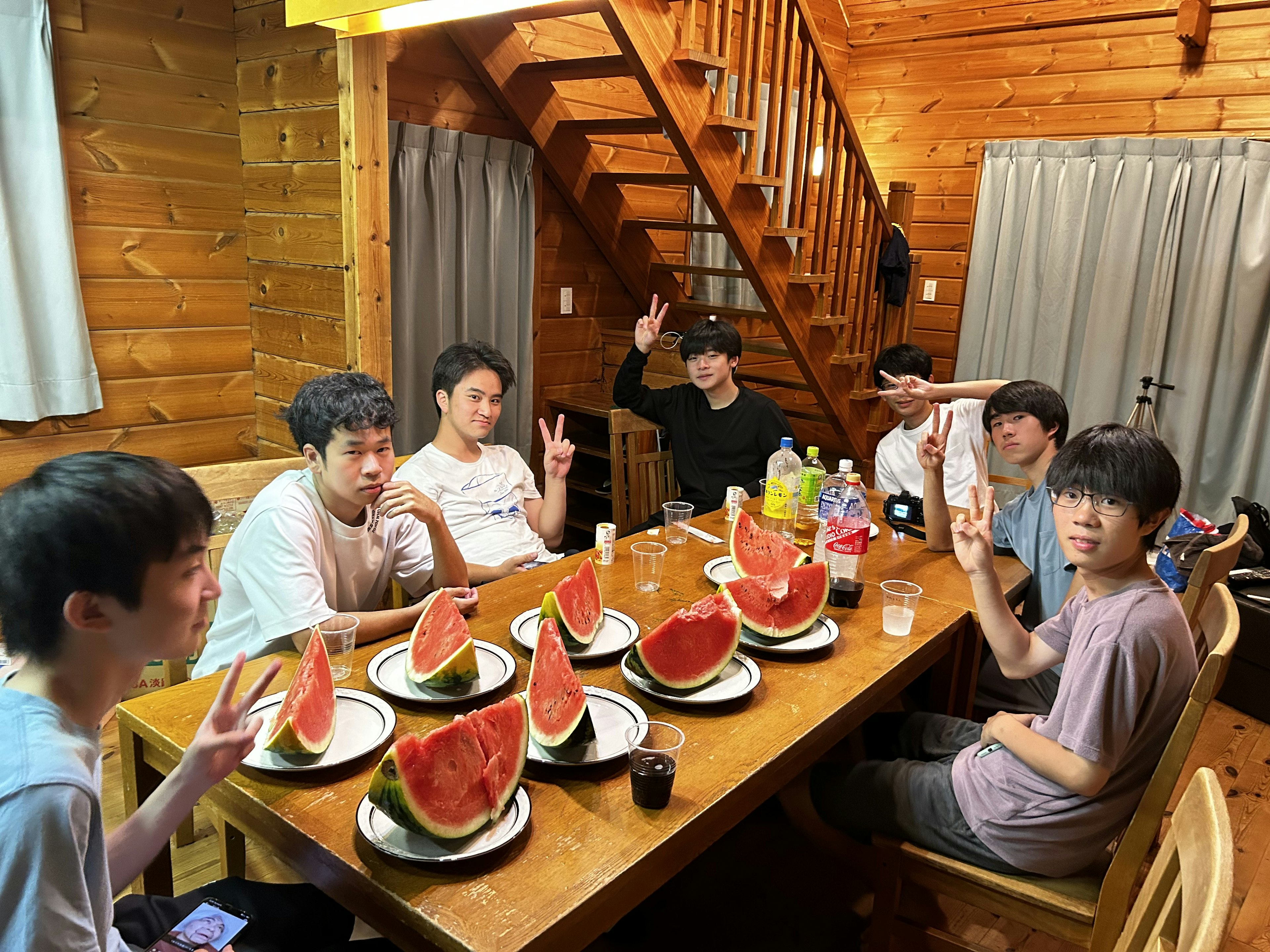 Group of young people enjoying watermelon at a wooden table