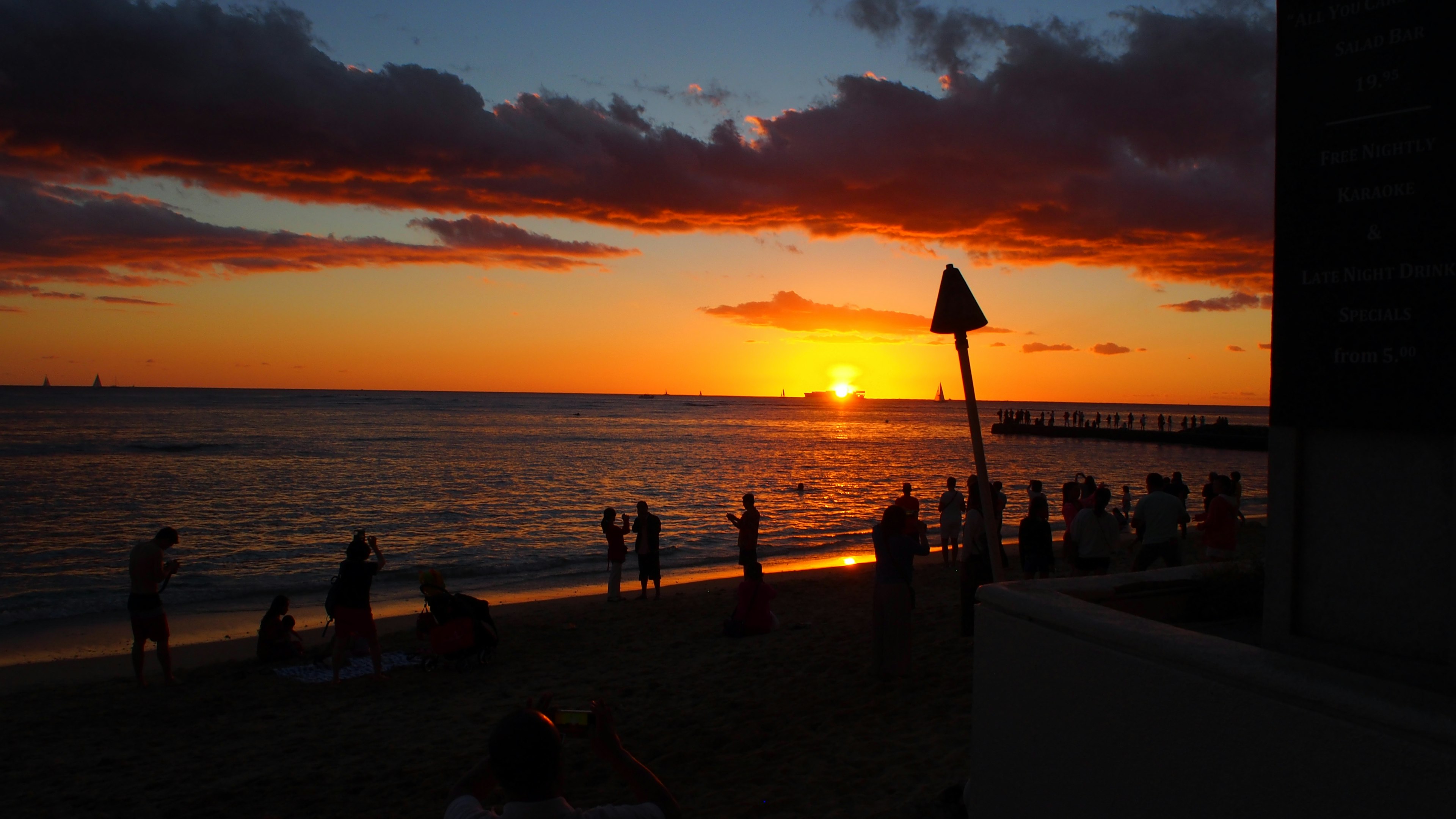 夕日が海に沈む美しいビーチの風景 人々がシルエットになっている