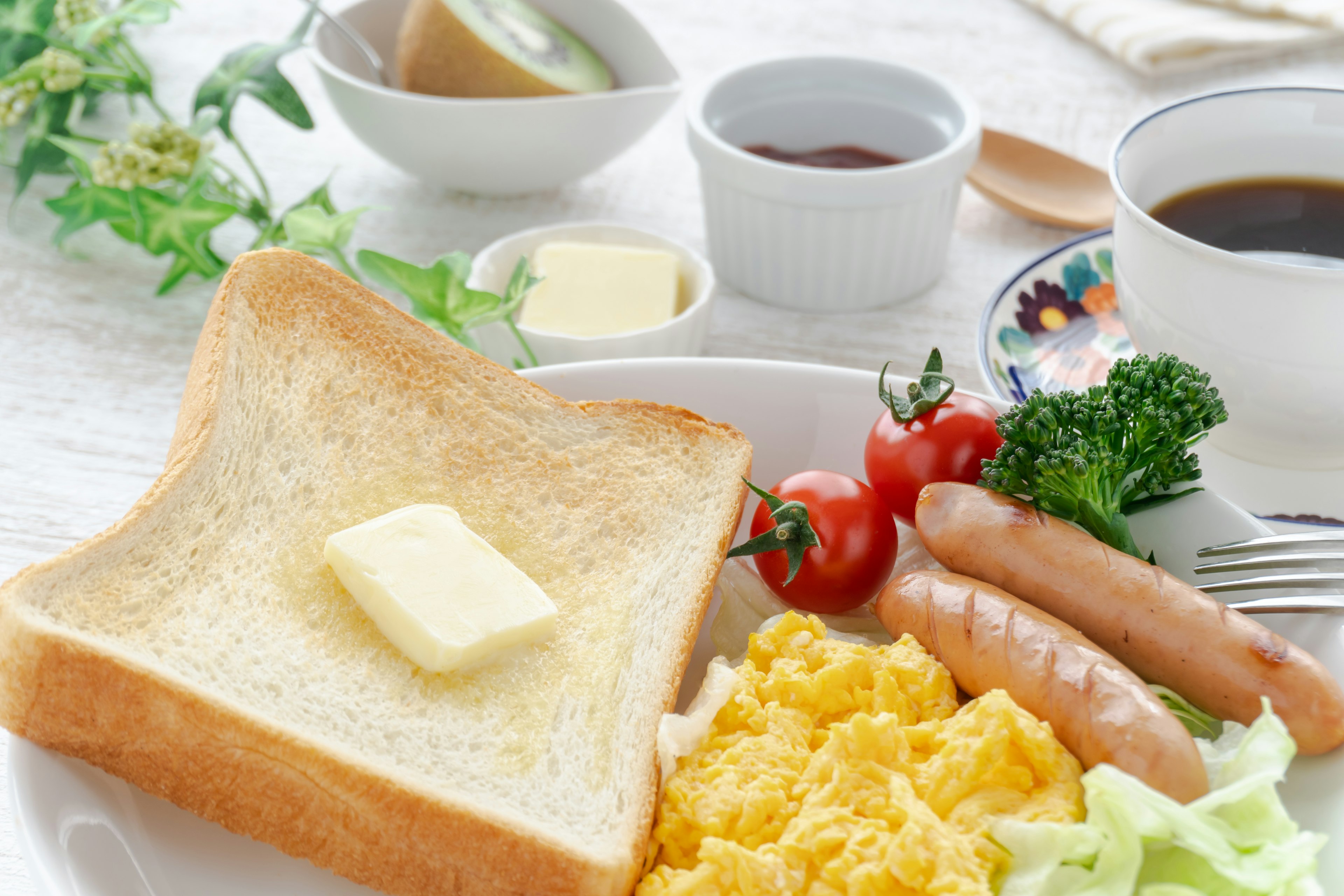 Frühstücksteller mit Toast mit Butter Rührei Würstchen Tomaten Brokkoli und Salat