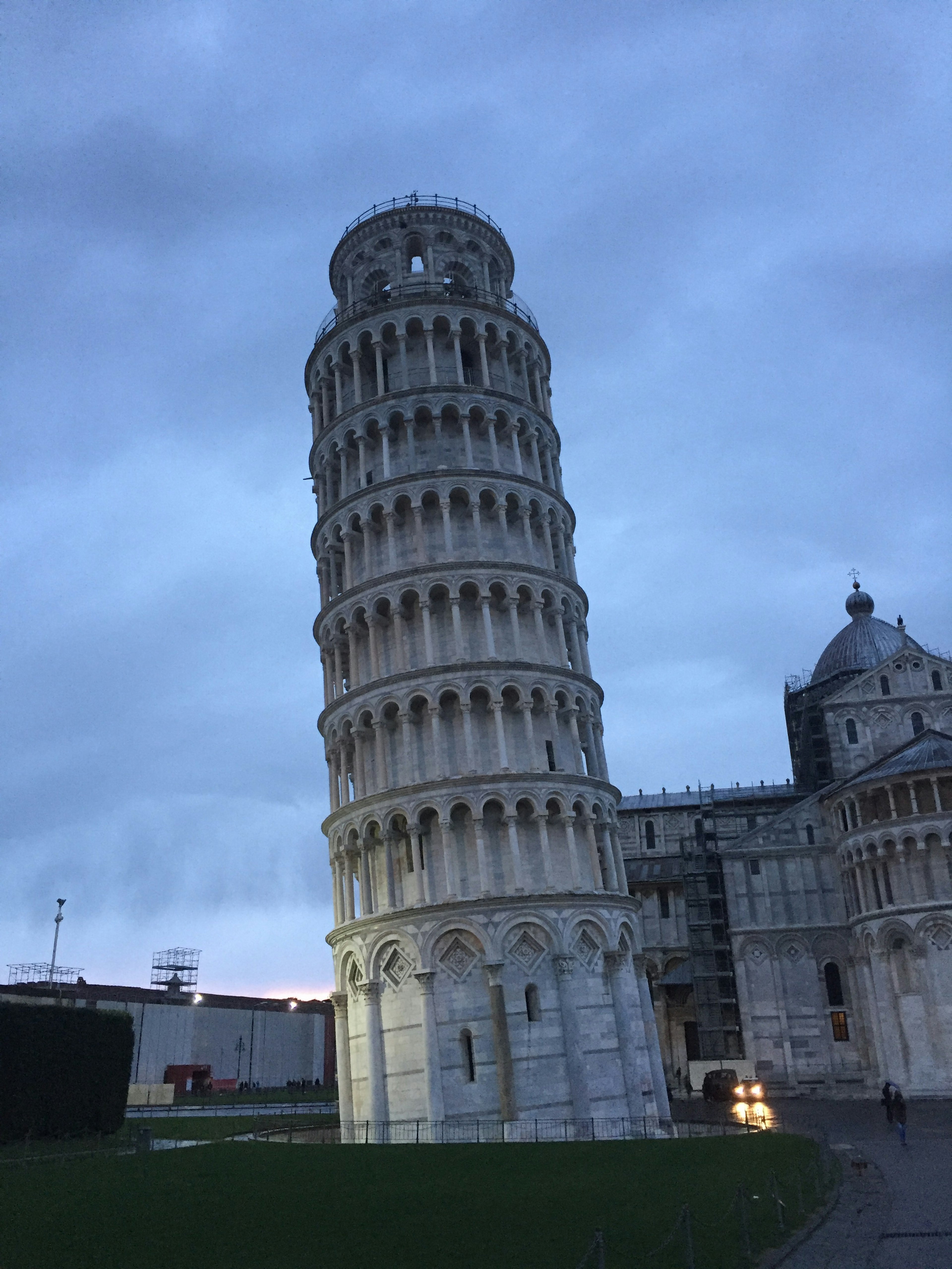 Schiefer Turm von Pisa in der Dämmerung mit seiner ikonischen weißen Kalksteinstruktur und blauem Himmel