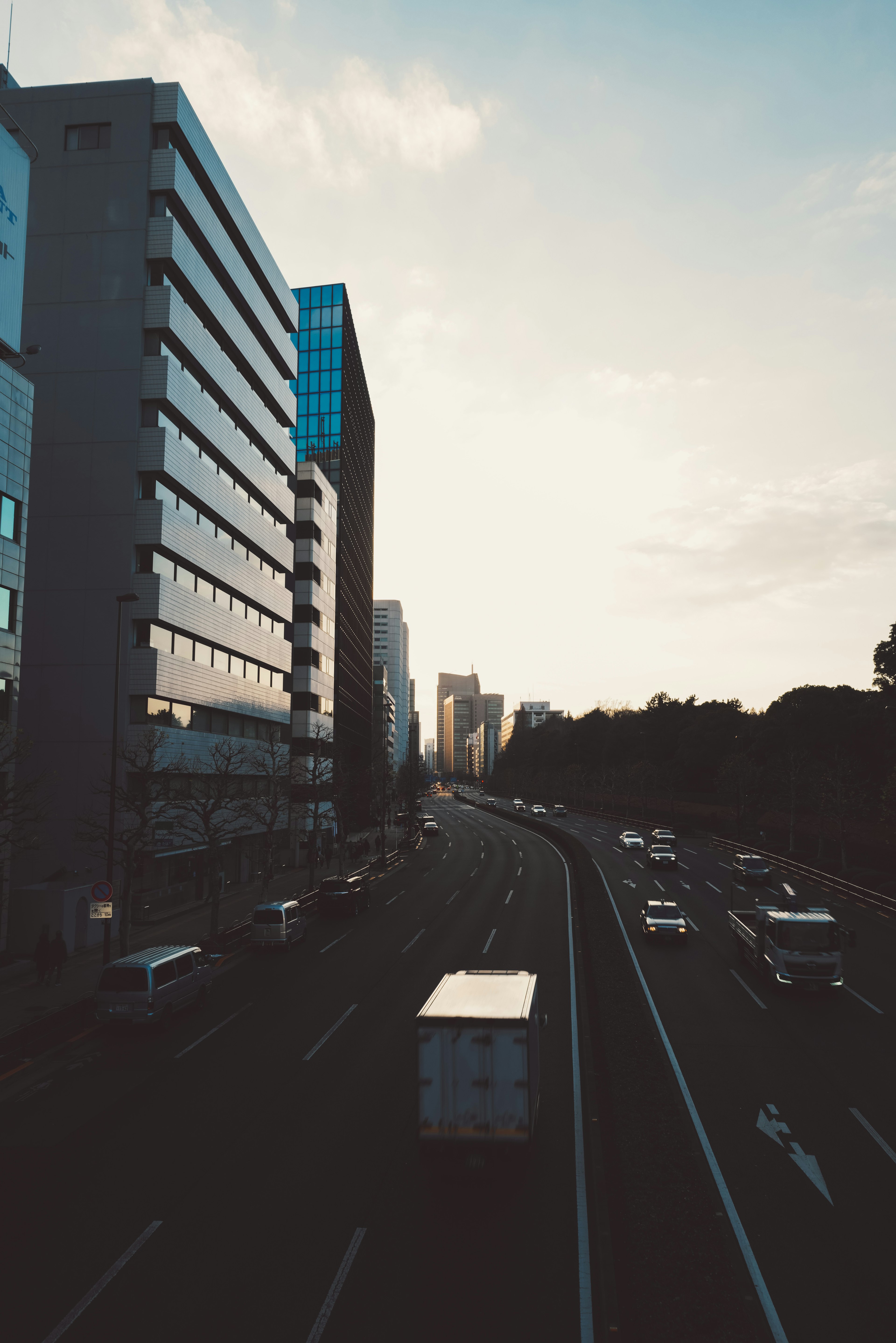 Paisaje urbano al atardecer con edificios y vehículos en la carretera