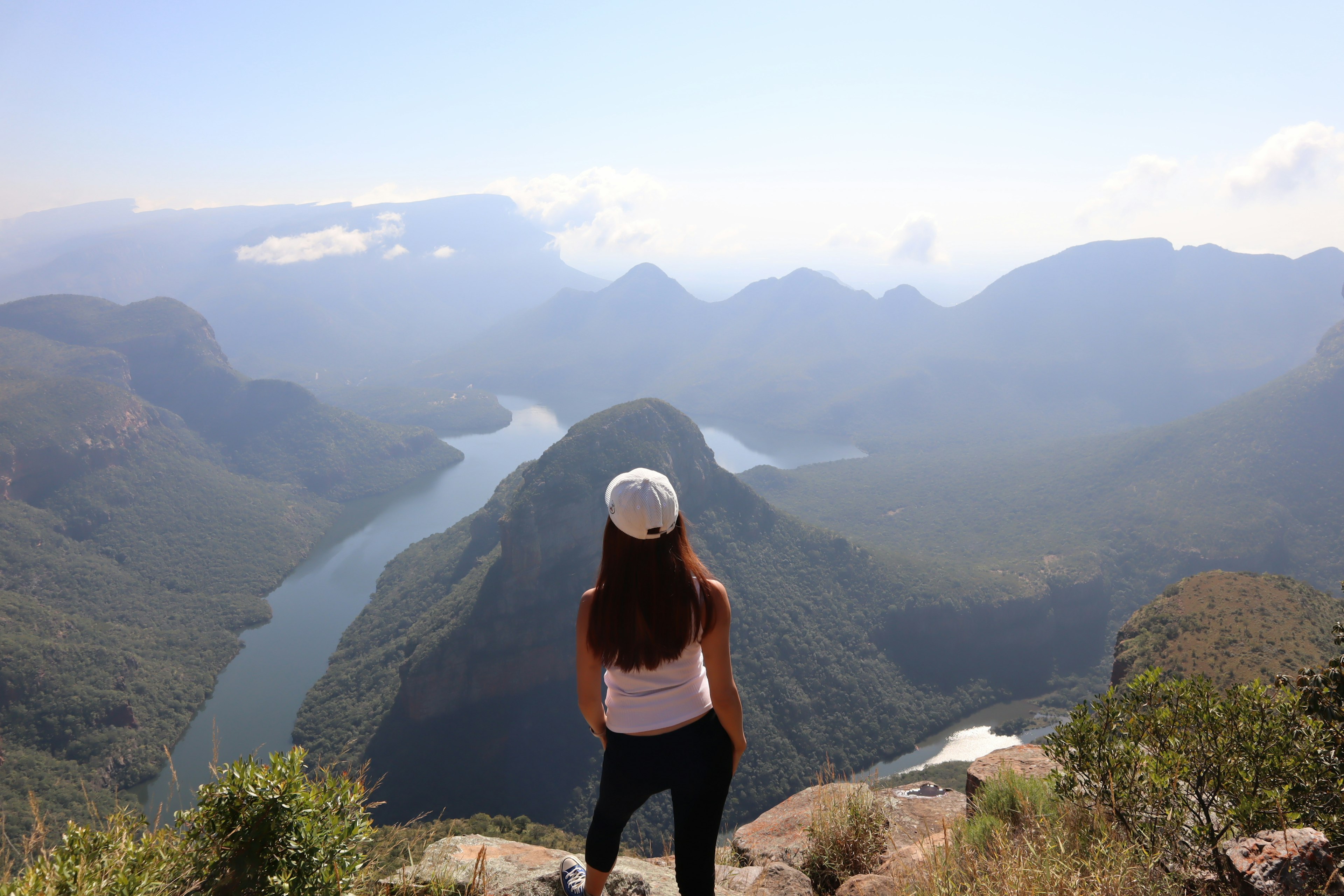 Mujer mirando un lago pintoresco rodeado de montañas