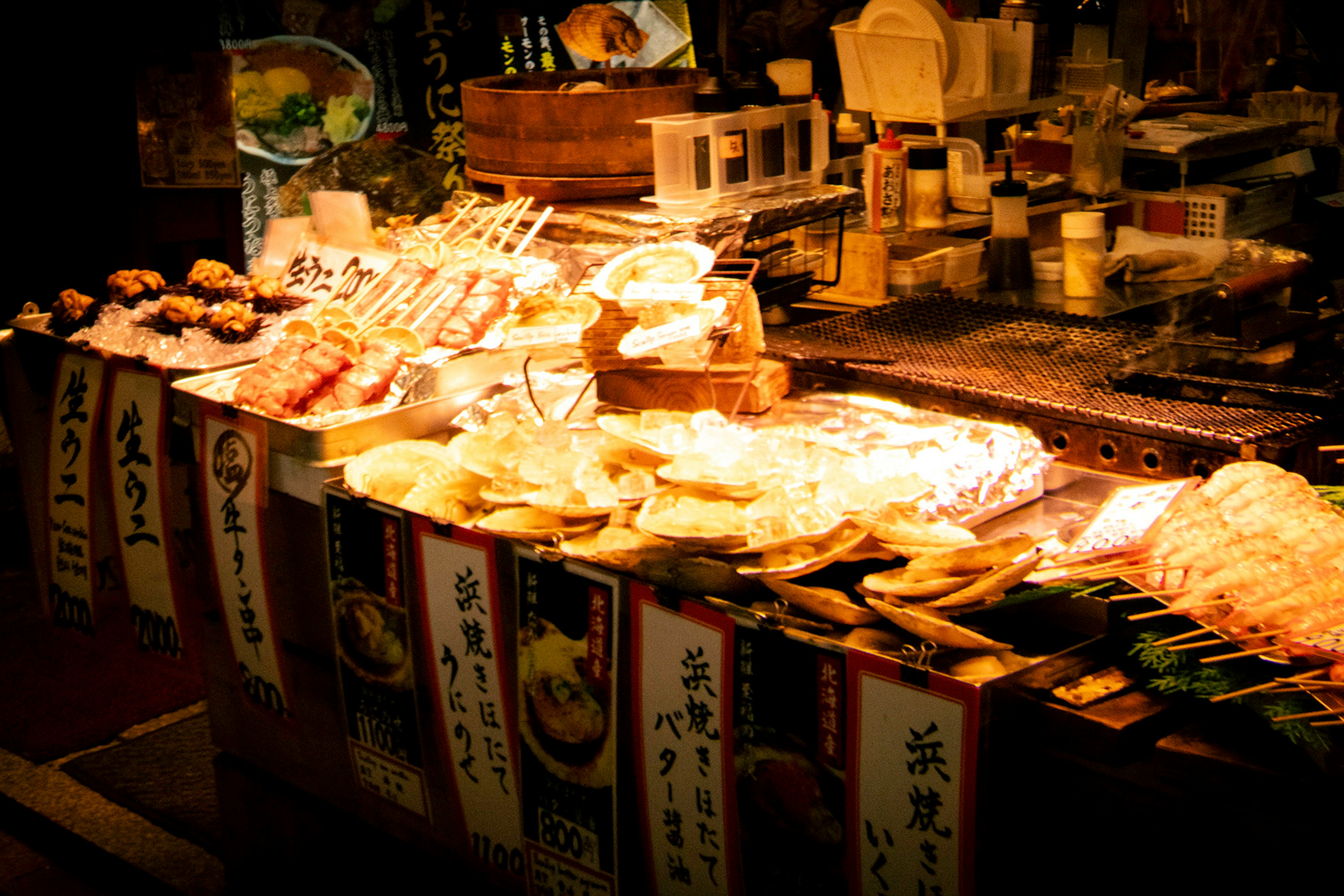 Puesto de mercado nocturno que exhibe varios alimentos y platos