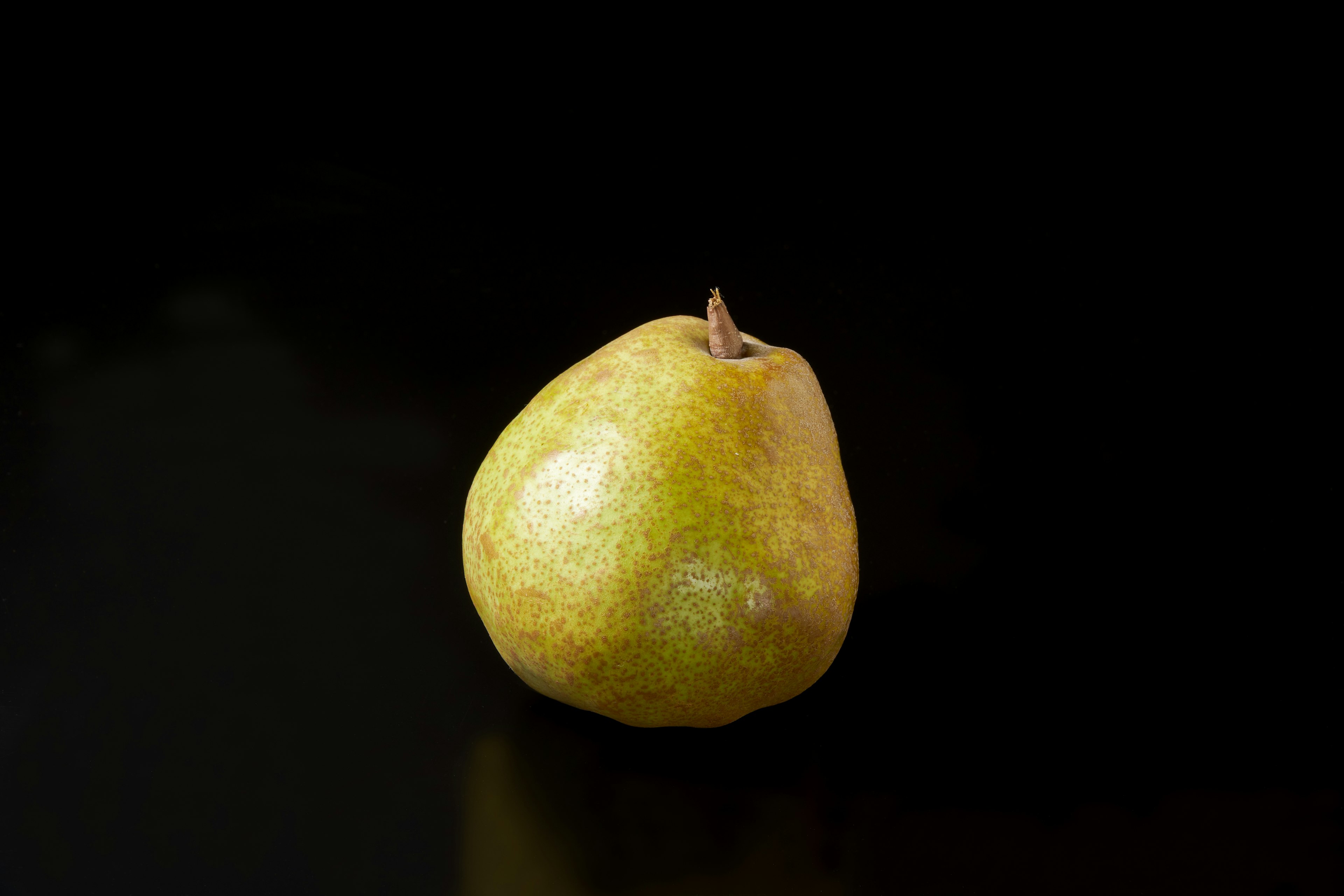 A yellow pear on a black background