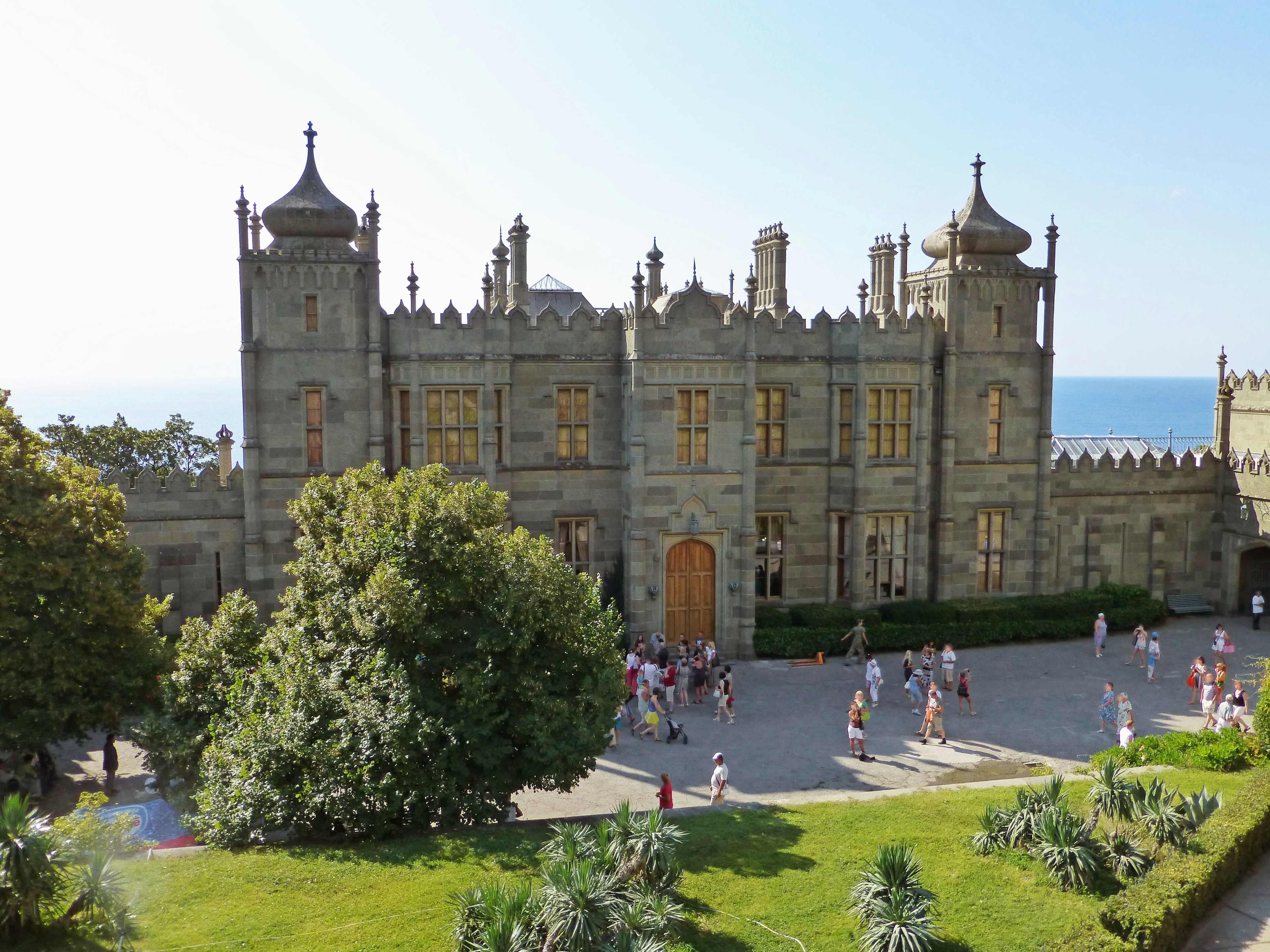 Belle façade de château face à la mer avec des visiteurs