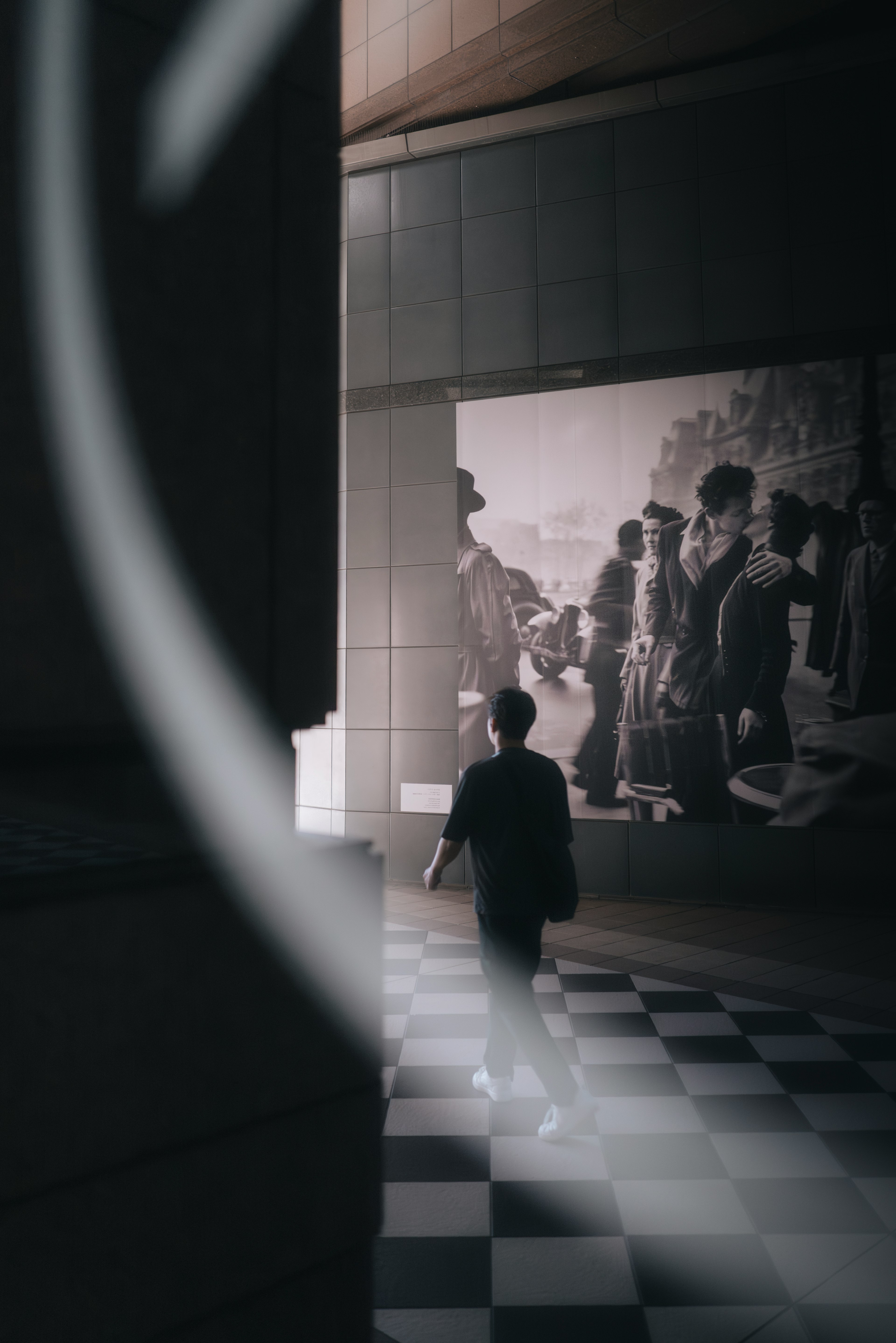 Una persona caminando sobre un suelo a cuadros con un fondo de foto histórica