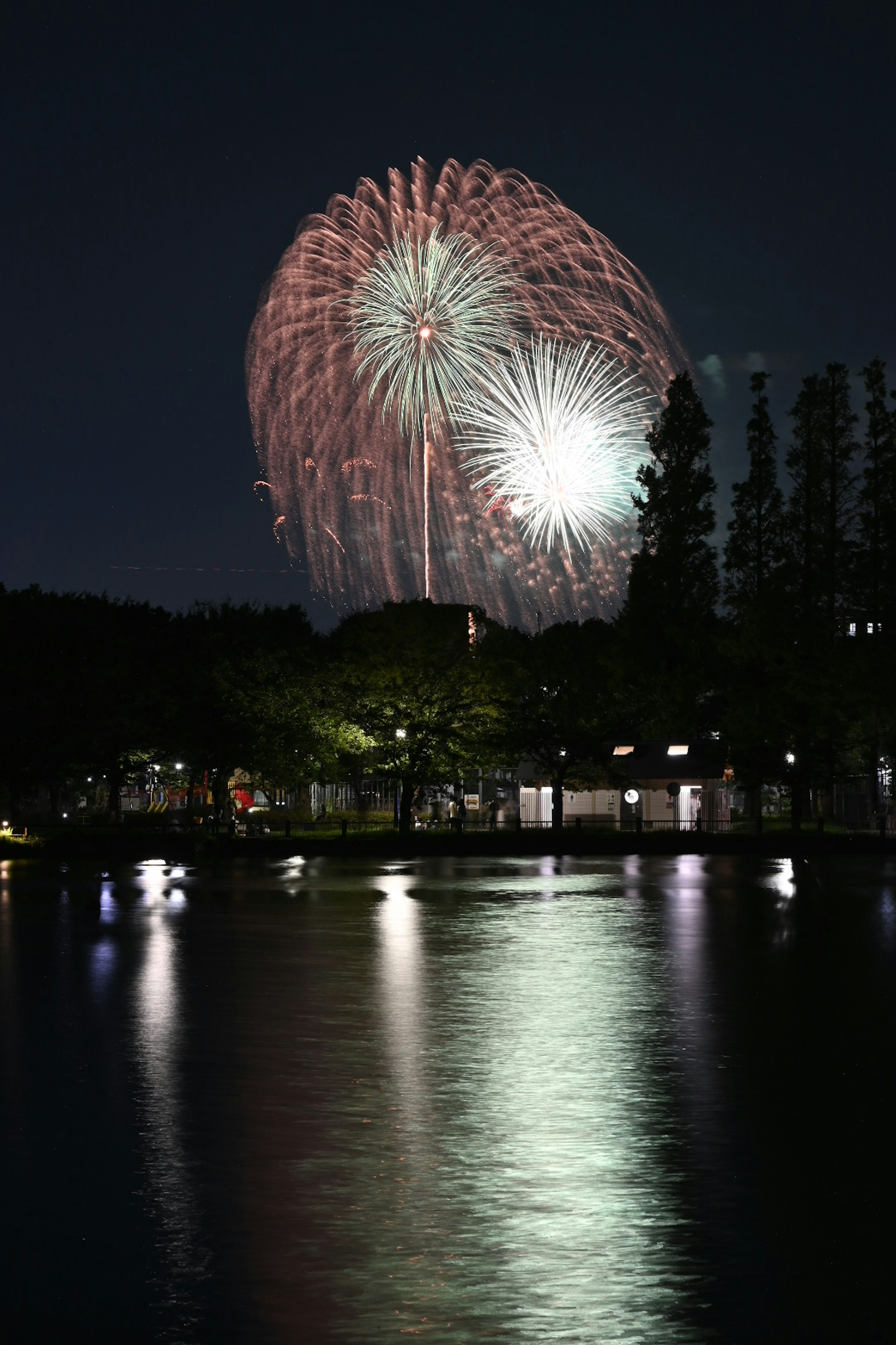 夜空に花火が打ち上げられ水面に反射する美しい光景