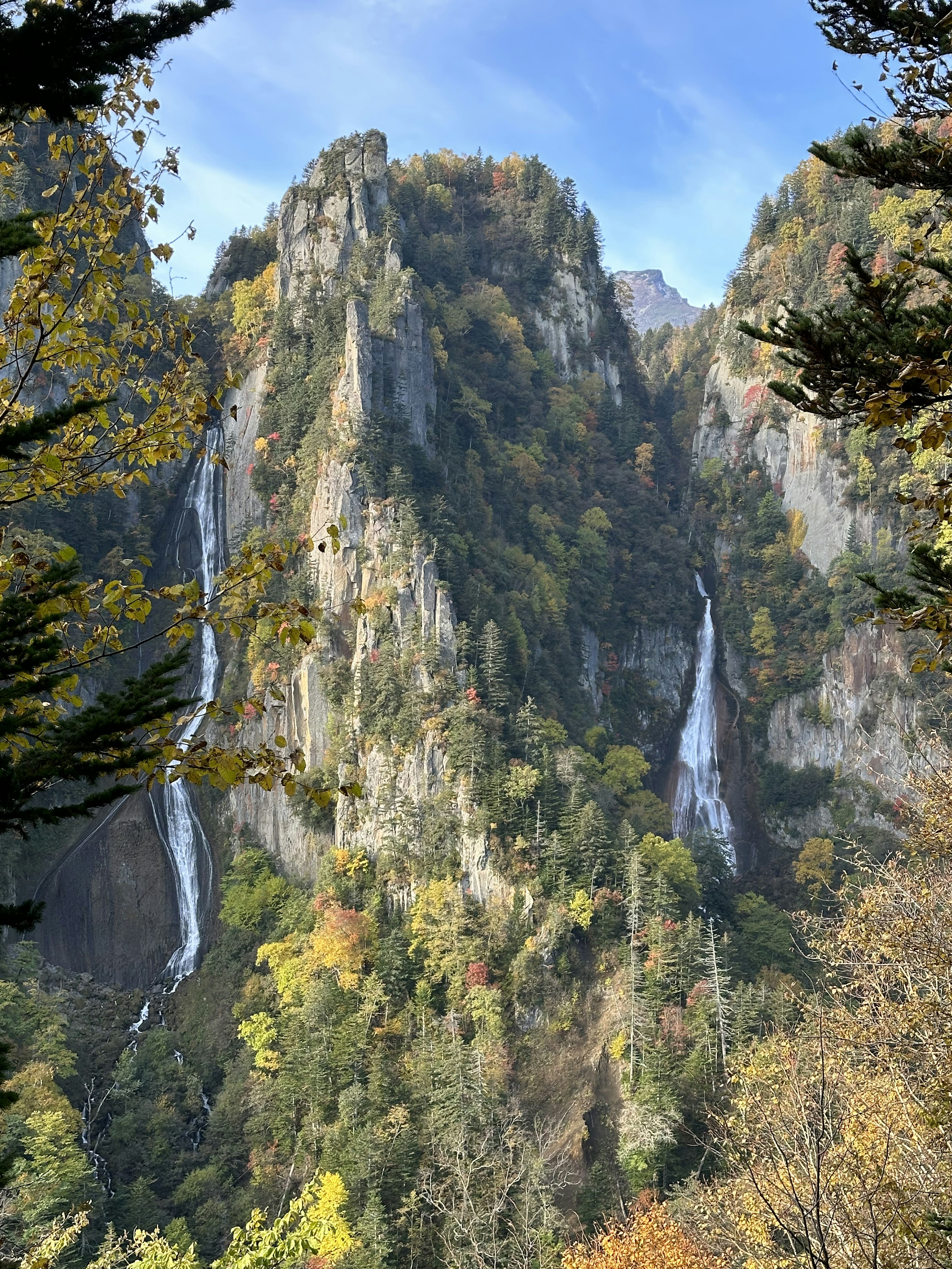 秋の色合いの滝が流れる山々の風景