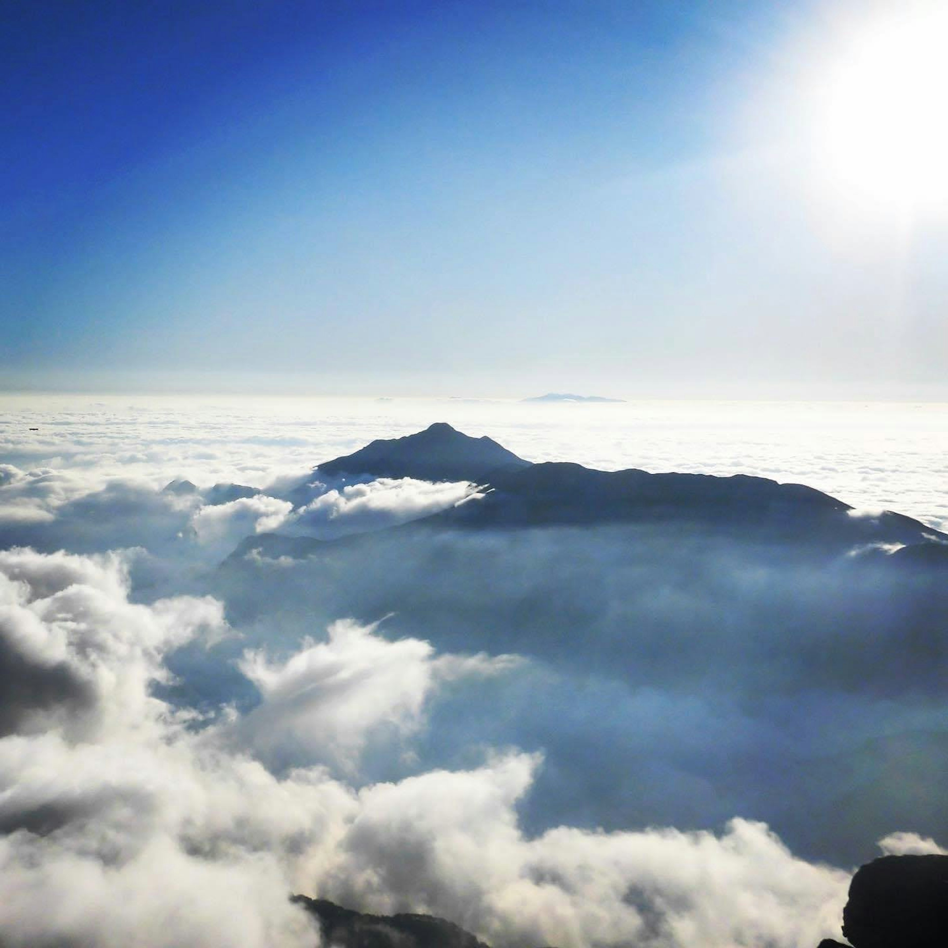 Paisaje montañoso sobre un mar de nubes con cielo azul