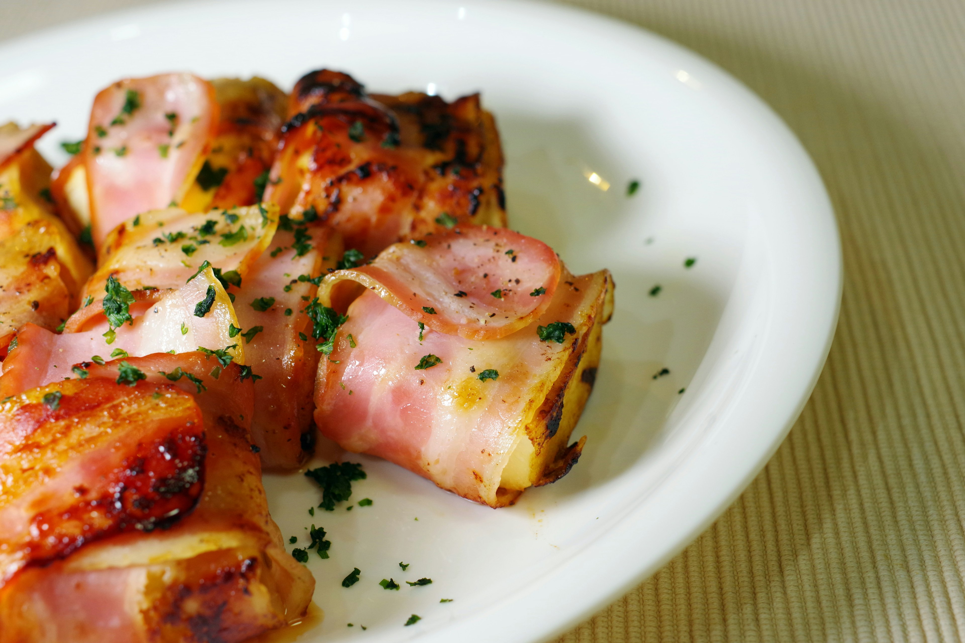 Cooked bacon wrapped dish garnished with parsley on a white plate