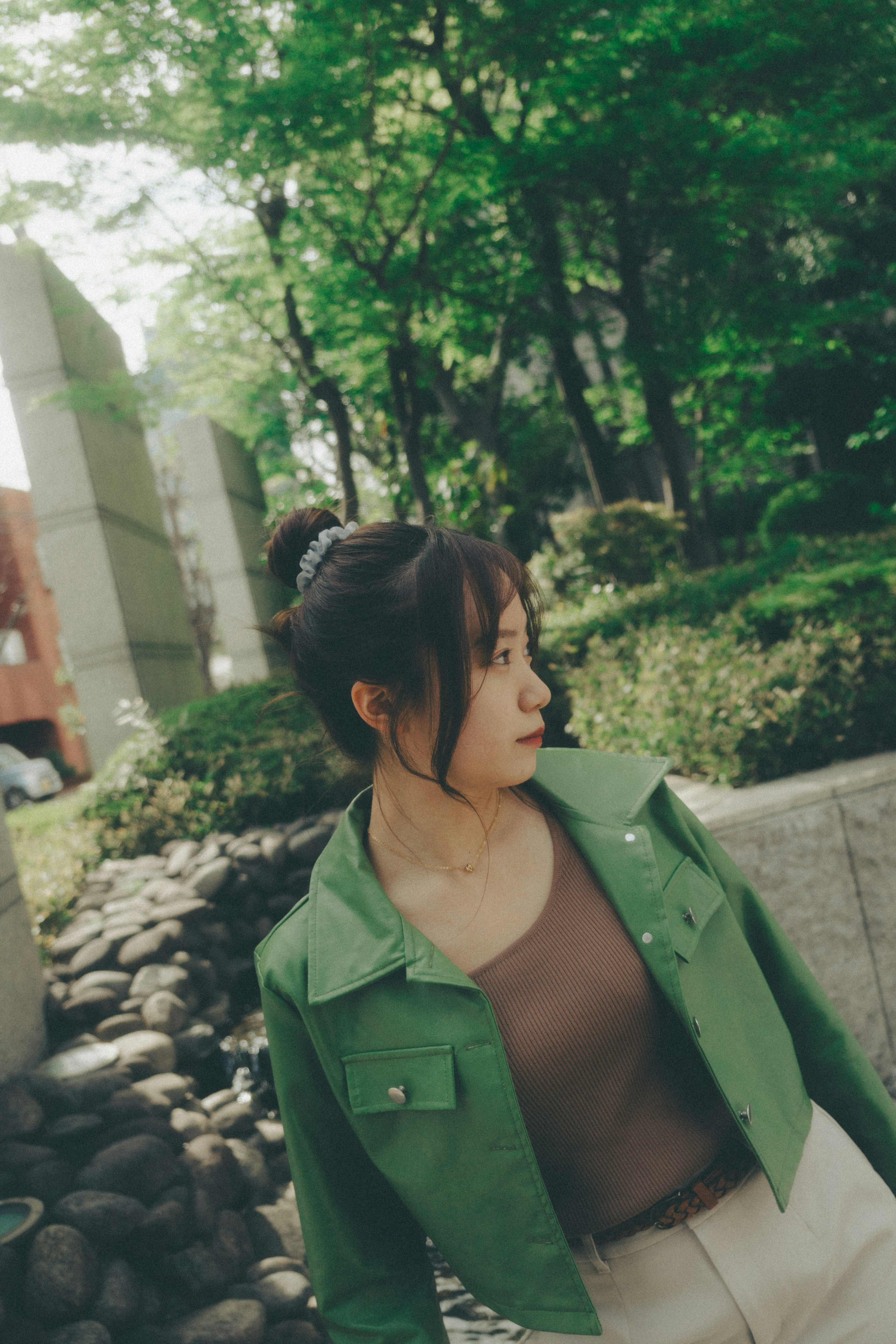 Una mujer con chaqueta verde girándose en un entorno natural