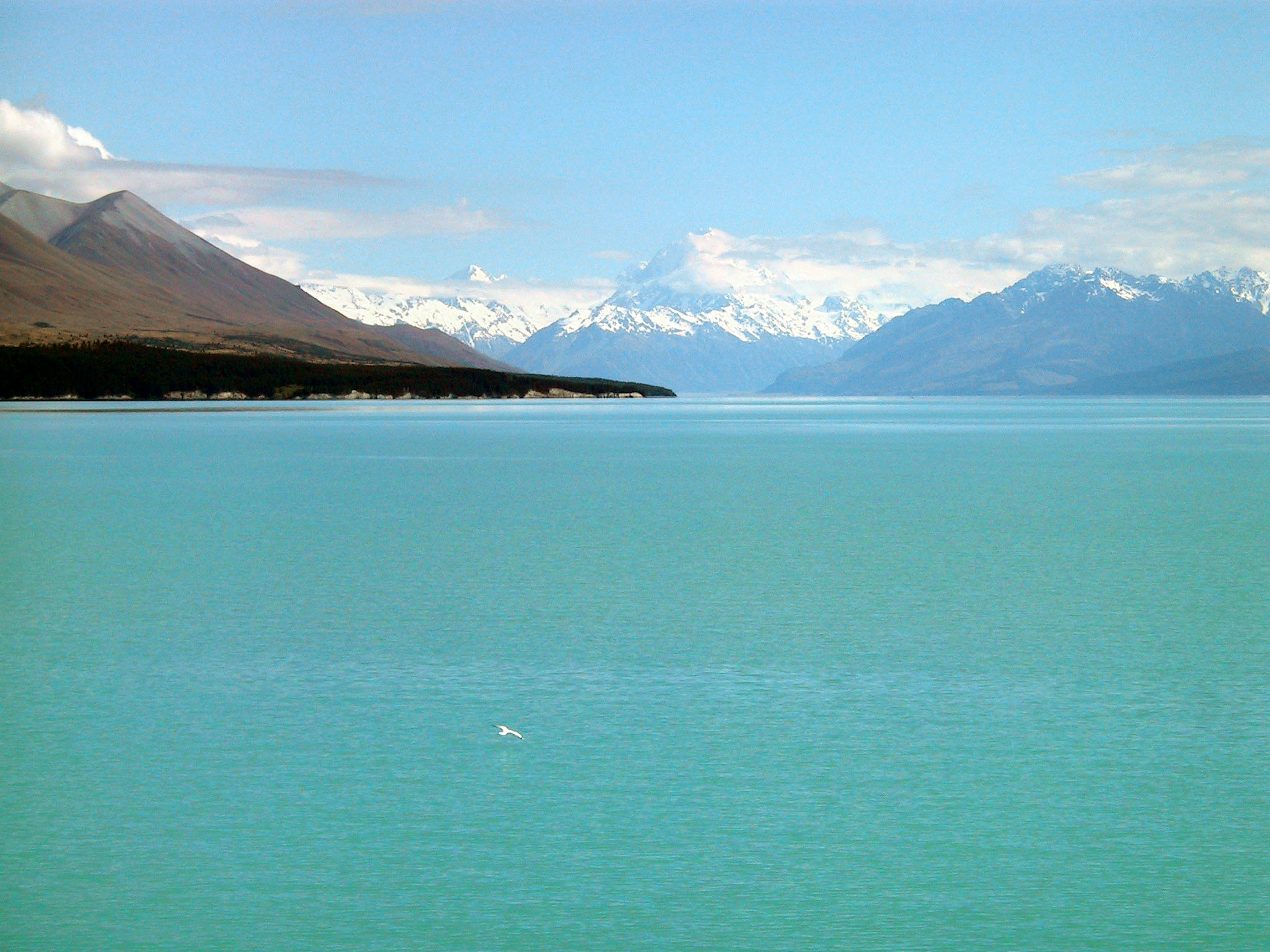 Vue panoramique d'un lac turquoise avec des montagnes enneigées