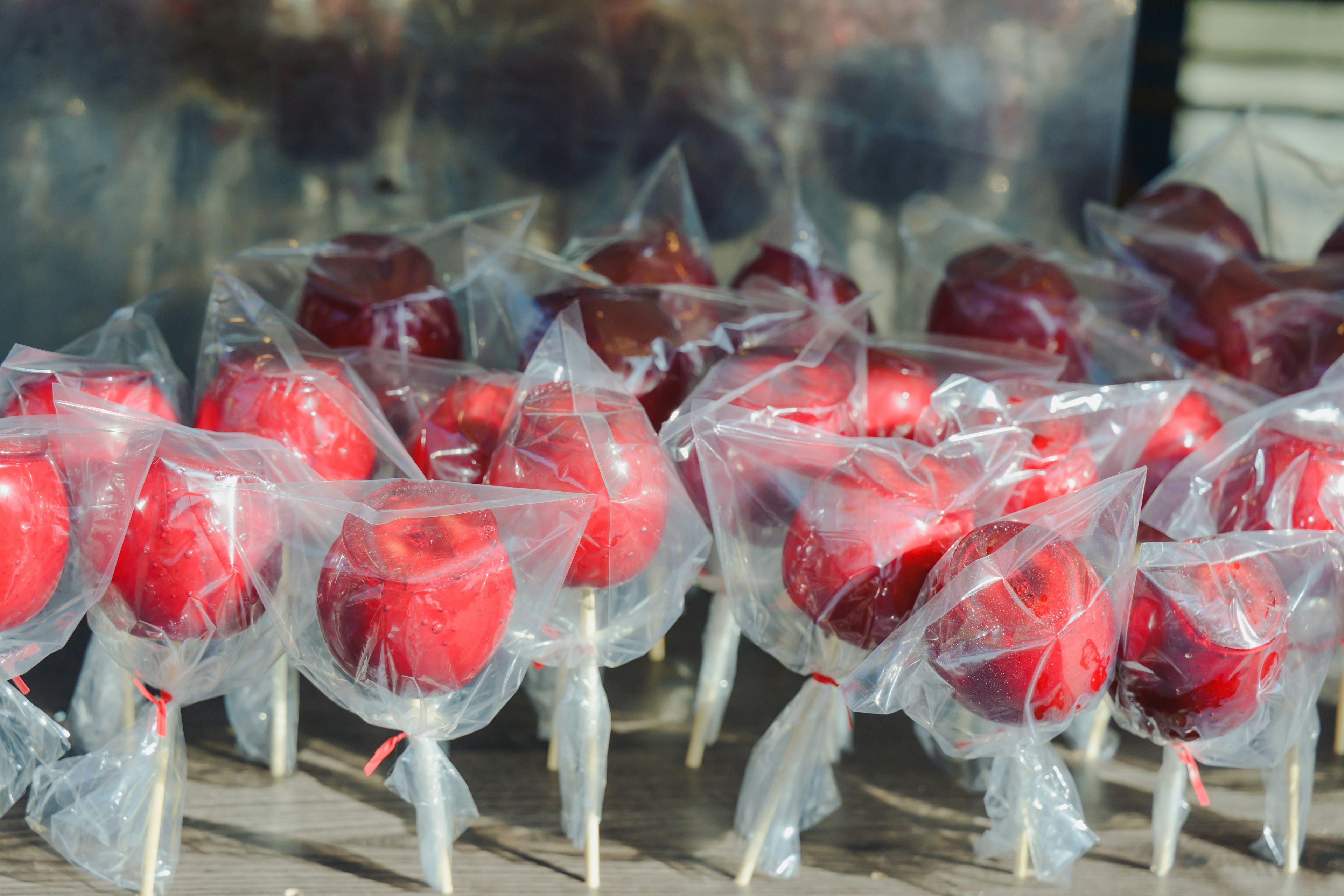 Pommes d'amour rouges enveloppées dans des sachets en plastique transparent disposées en rangées