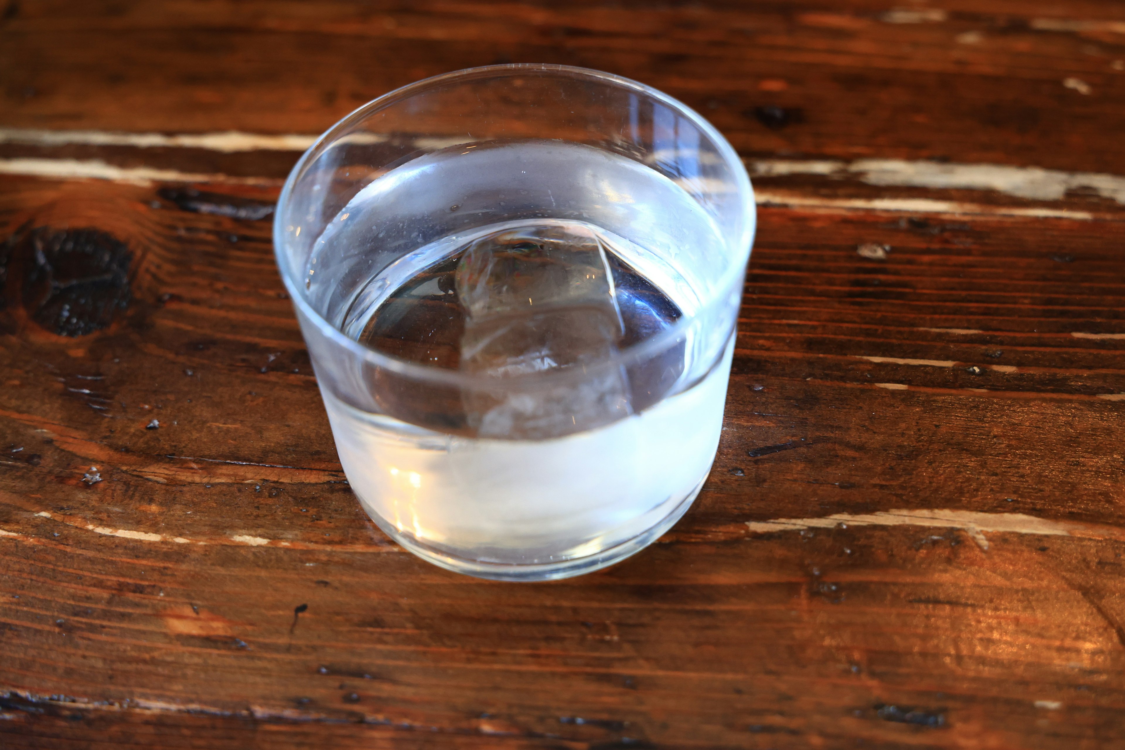 Vaso transparente con agua y hielo sobre una mesa de madera