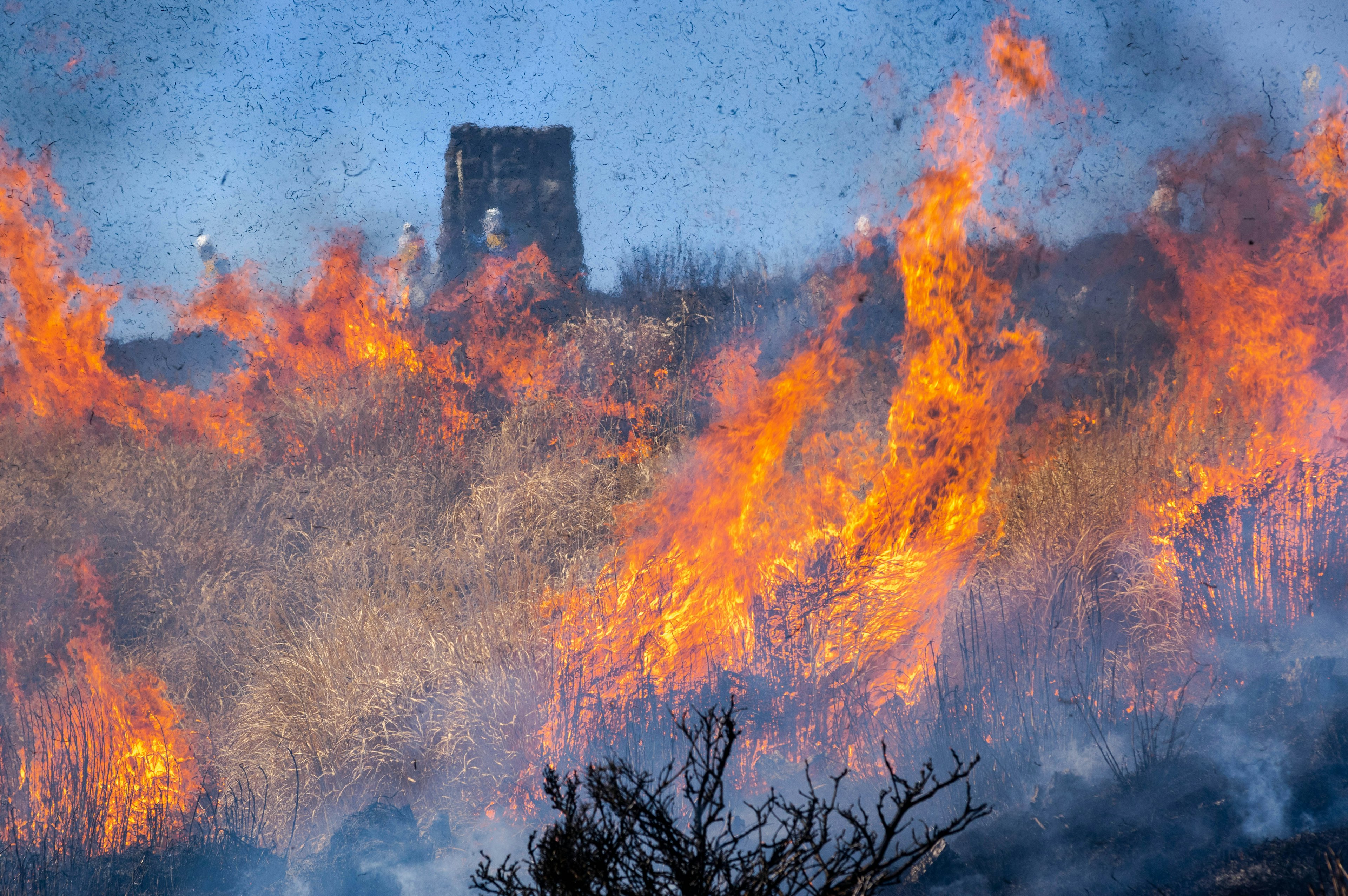 Tower in the background surrounded by flames and smoke