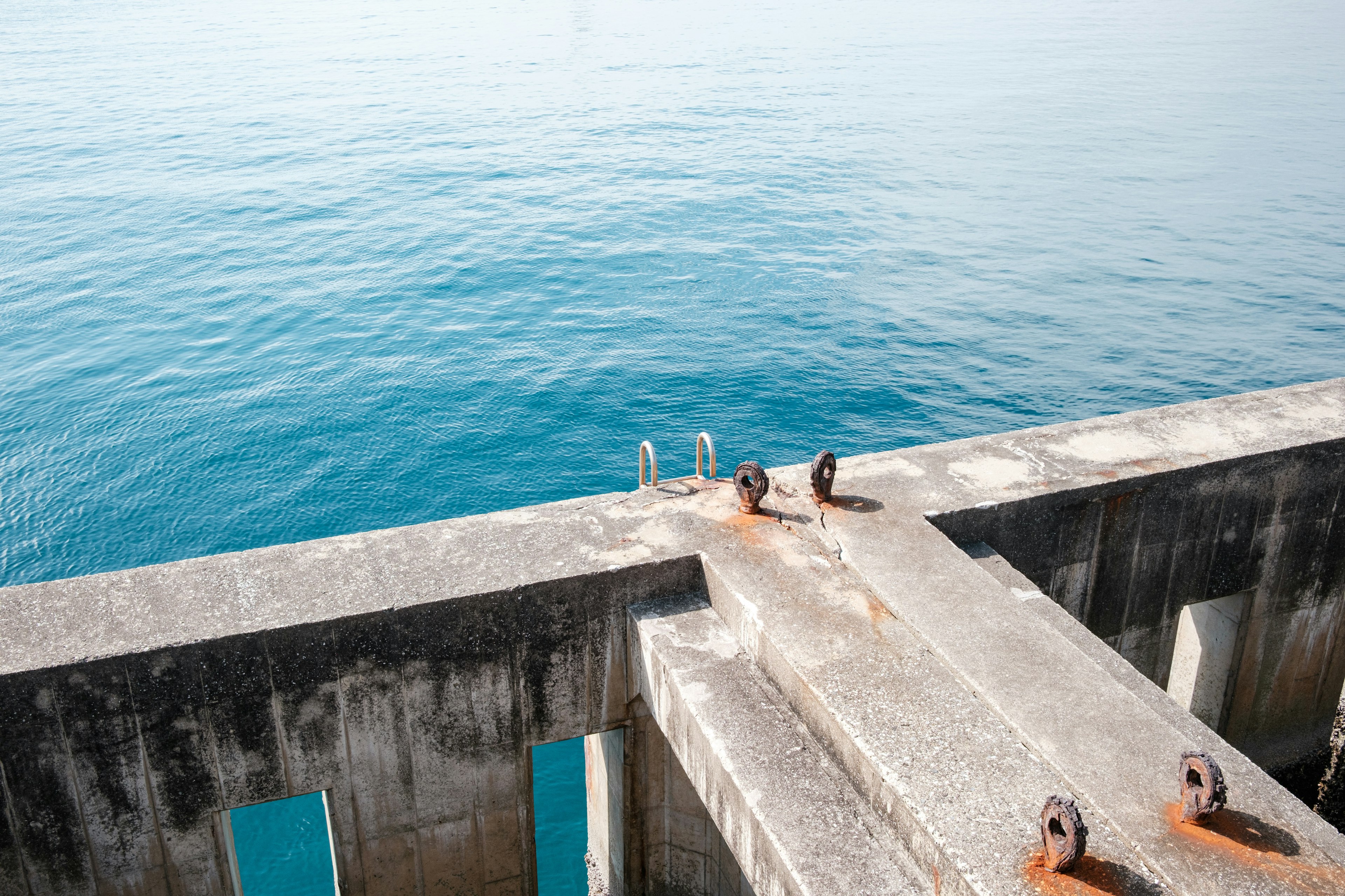 Muelle de concreto con accesorios metálicos que da al mar azul tranquilo