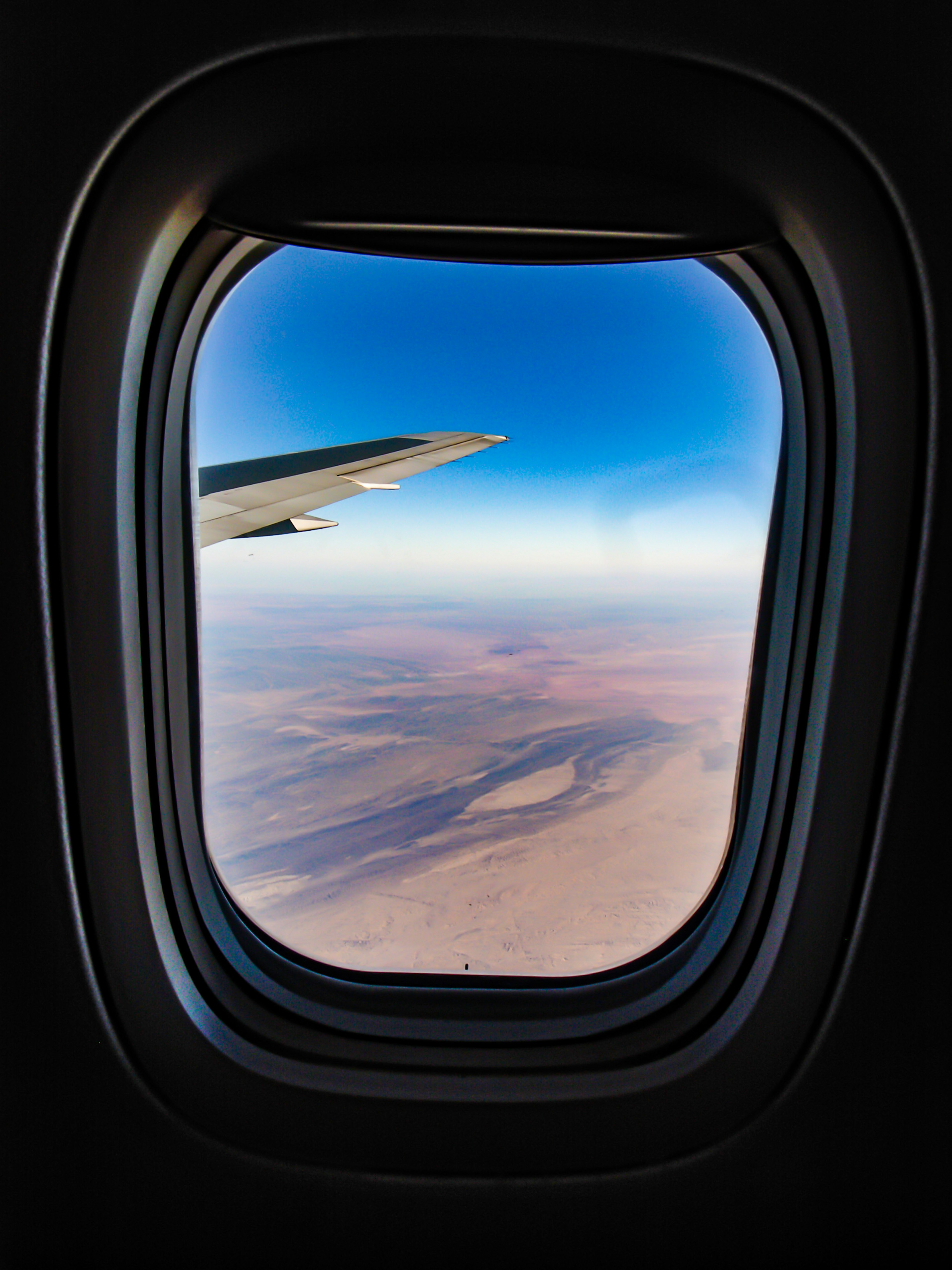 Blick aus einem Flugzeugfenster auf den Flügel und die Landschaft