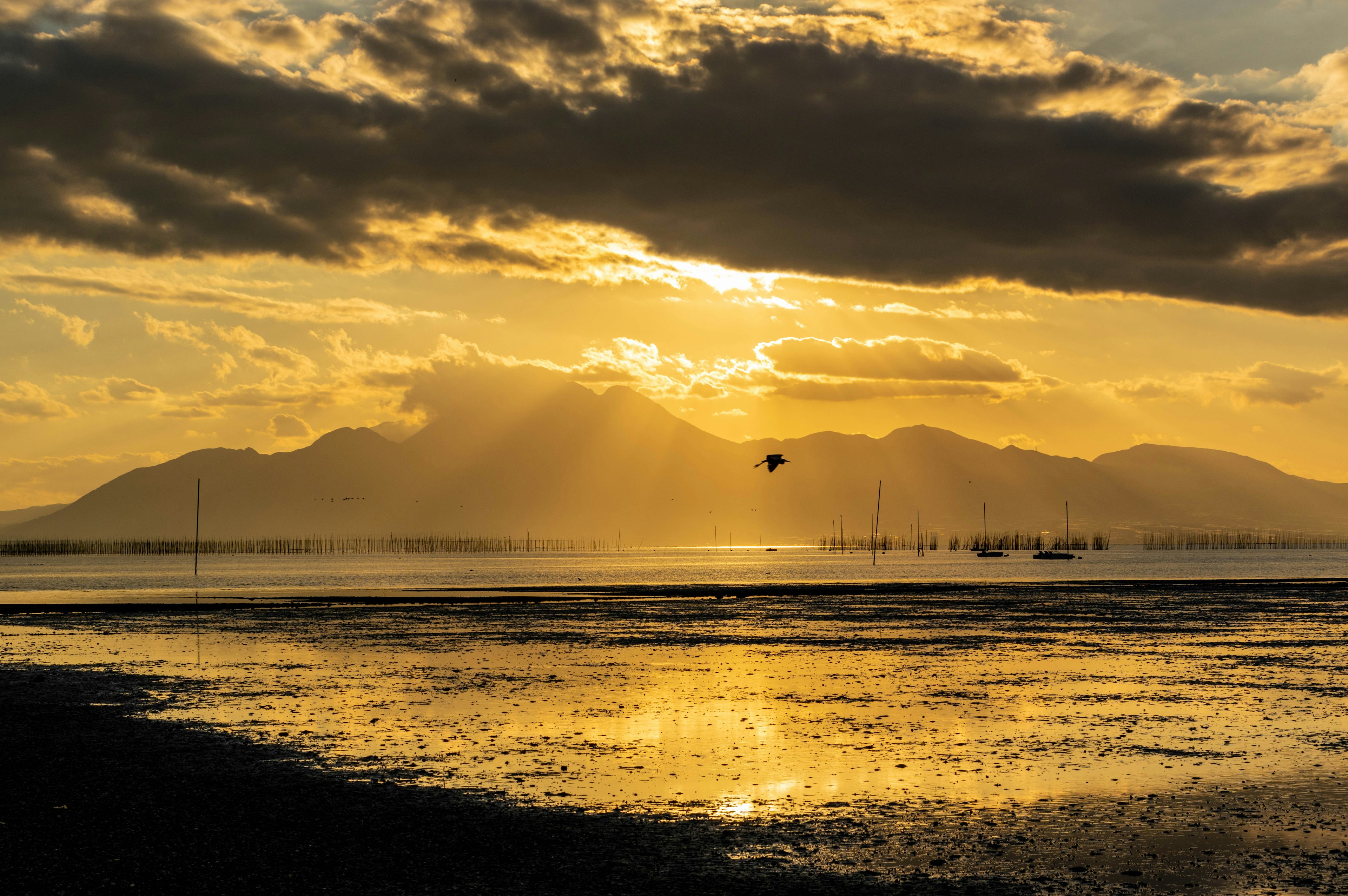 夕日が沈む海岸の風景で山々と雲が美しく照らされている