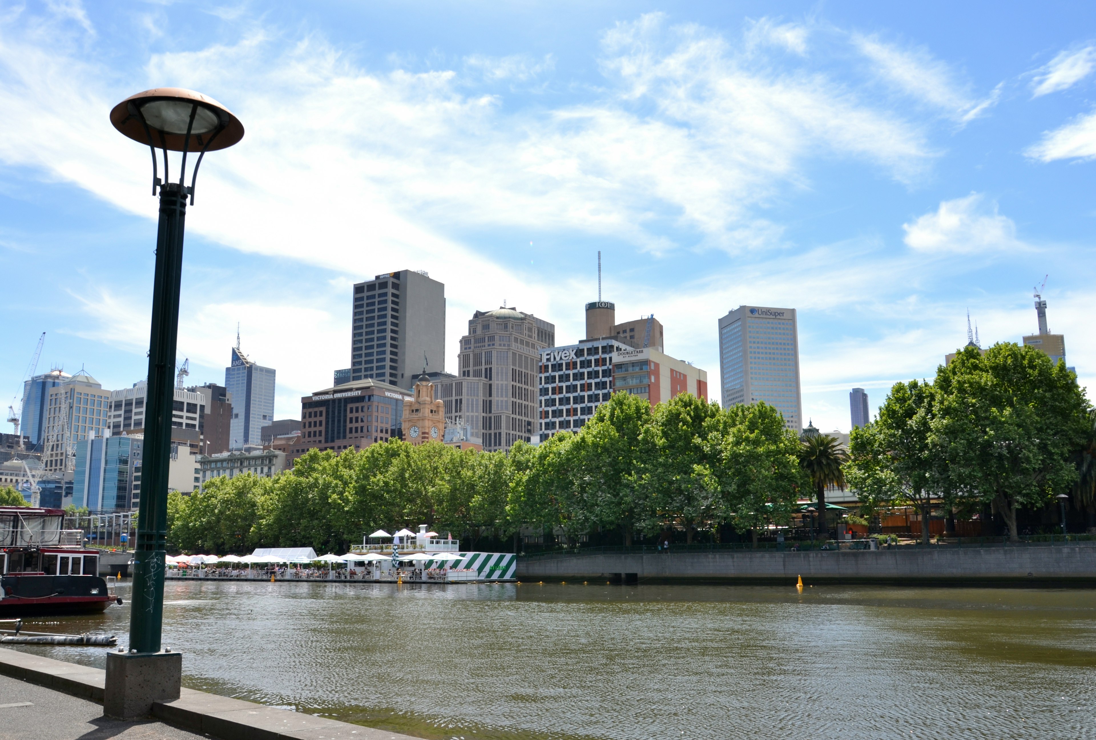 Städtische Landschaft von Melbourne entlang des Flusses mit grünen Bäumen und Wolkenkratzern