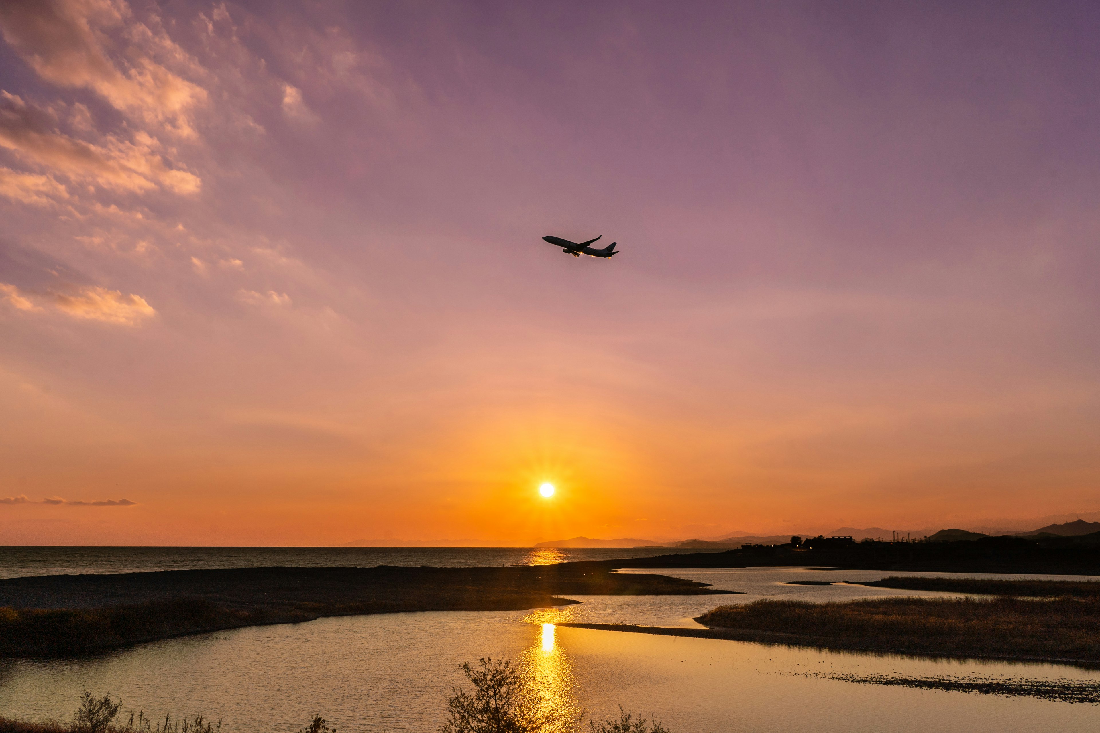 美しい夕日と飛行機が映る静かな水辺の風景